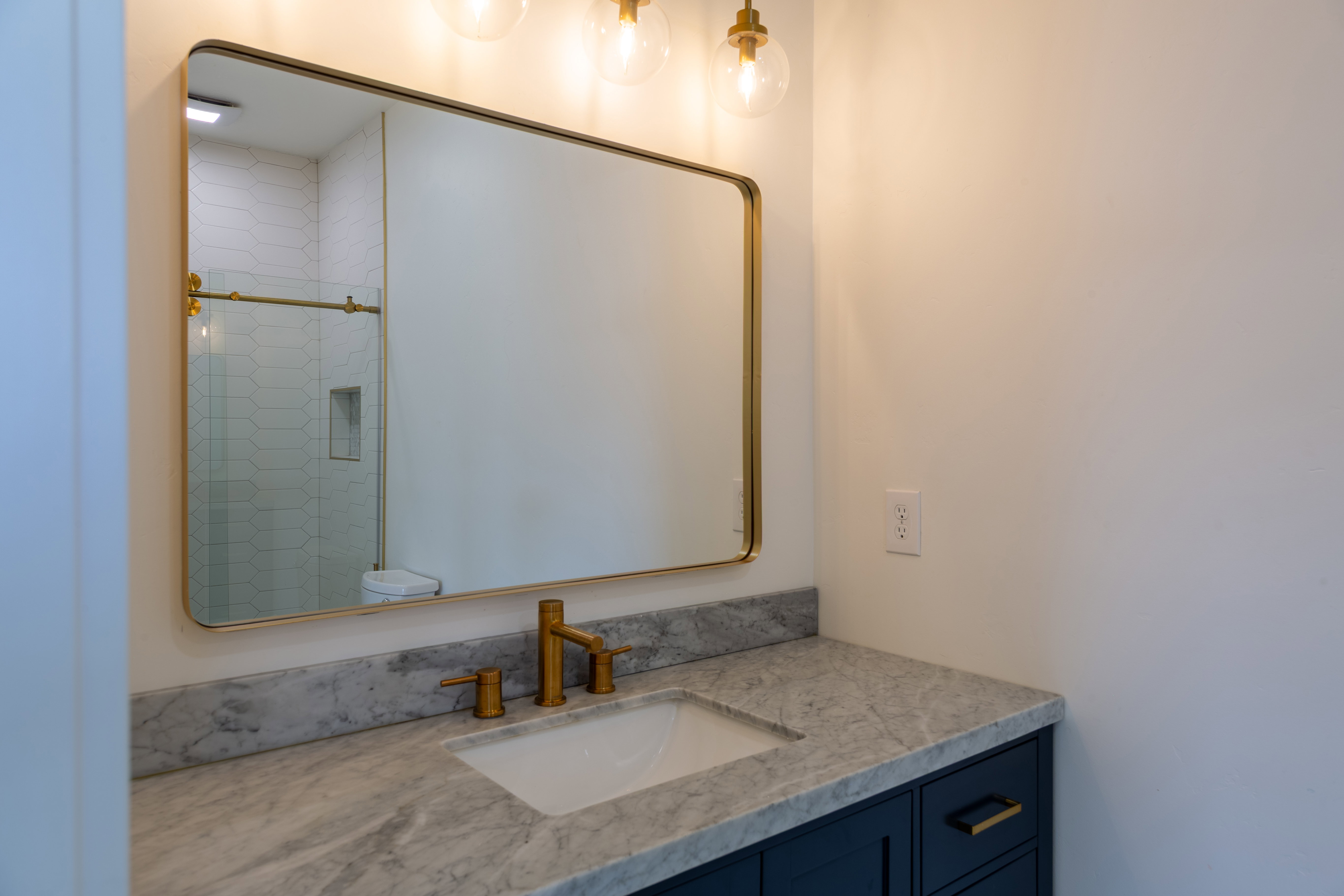 Bathroom vanity featuring a gold-framed mirror and three-light fixture
