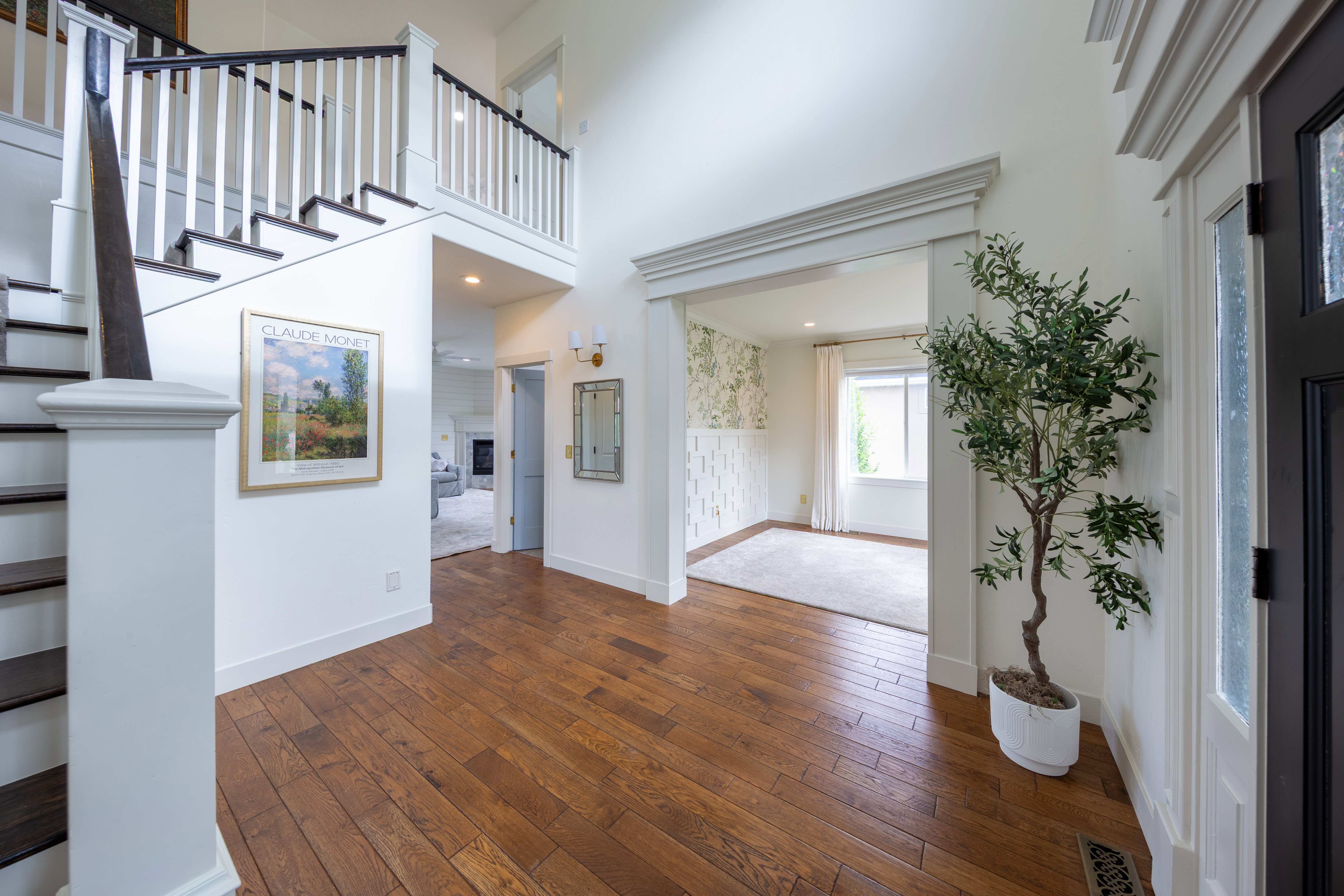 Grand entry foyer featuring wood-finish flooring, a prominent staircase with dark treads and white risers, and a two-story ceiling