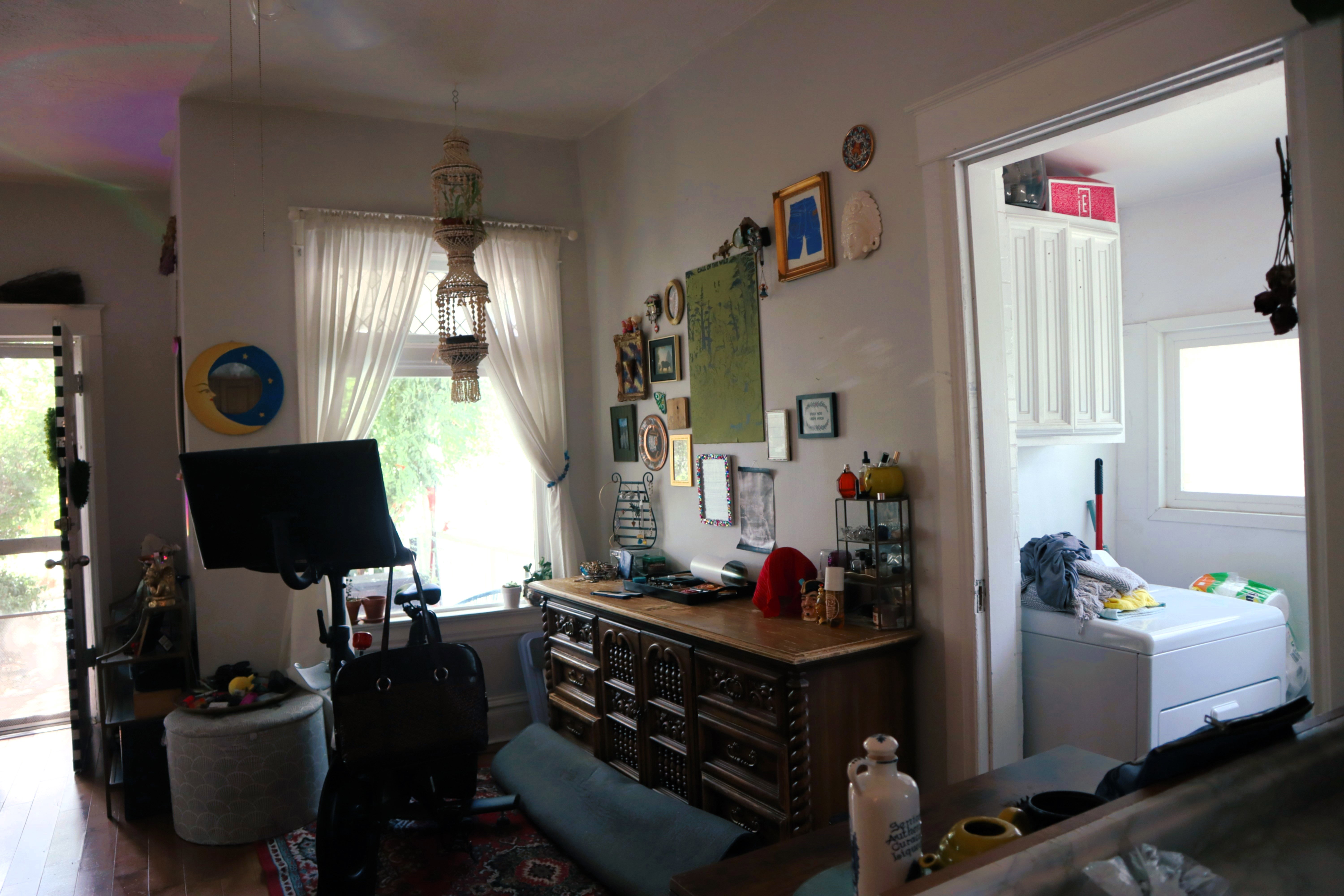 Interior room featuring wood-finish flooring and a window with white drapes