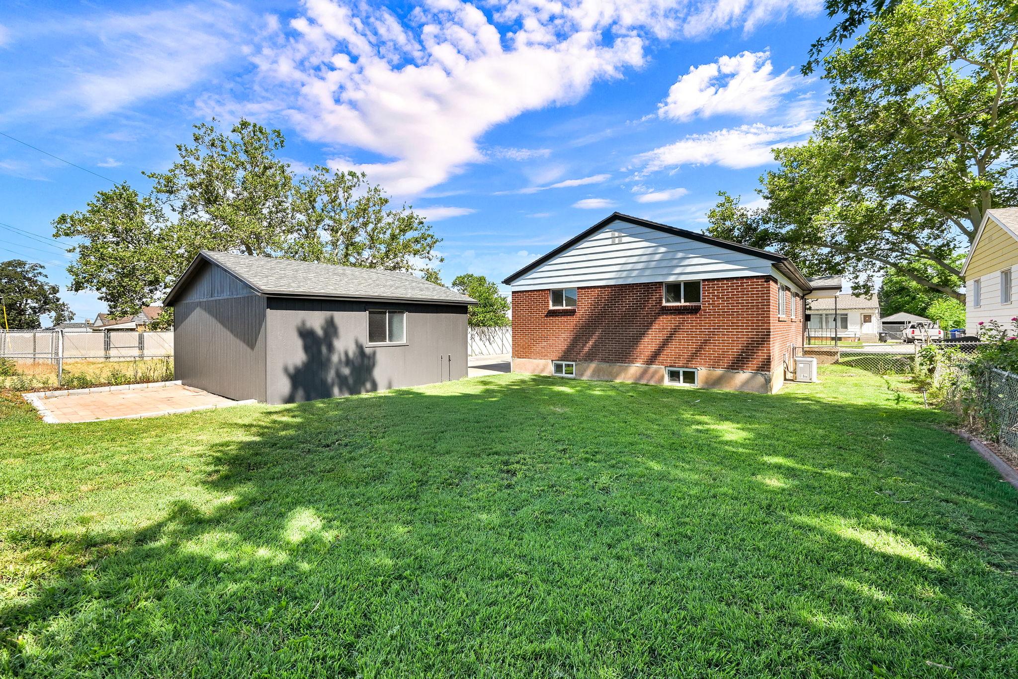 Expansive green lawn with a detached garage featuring a shingled roof and a window