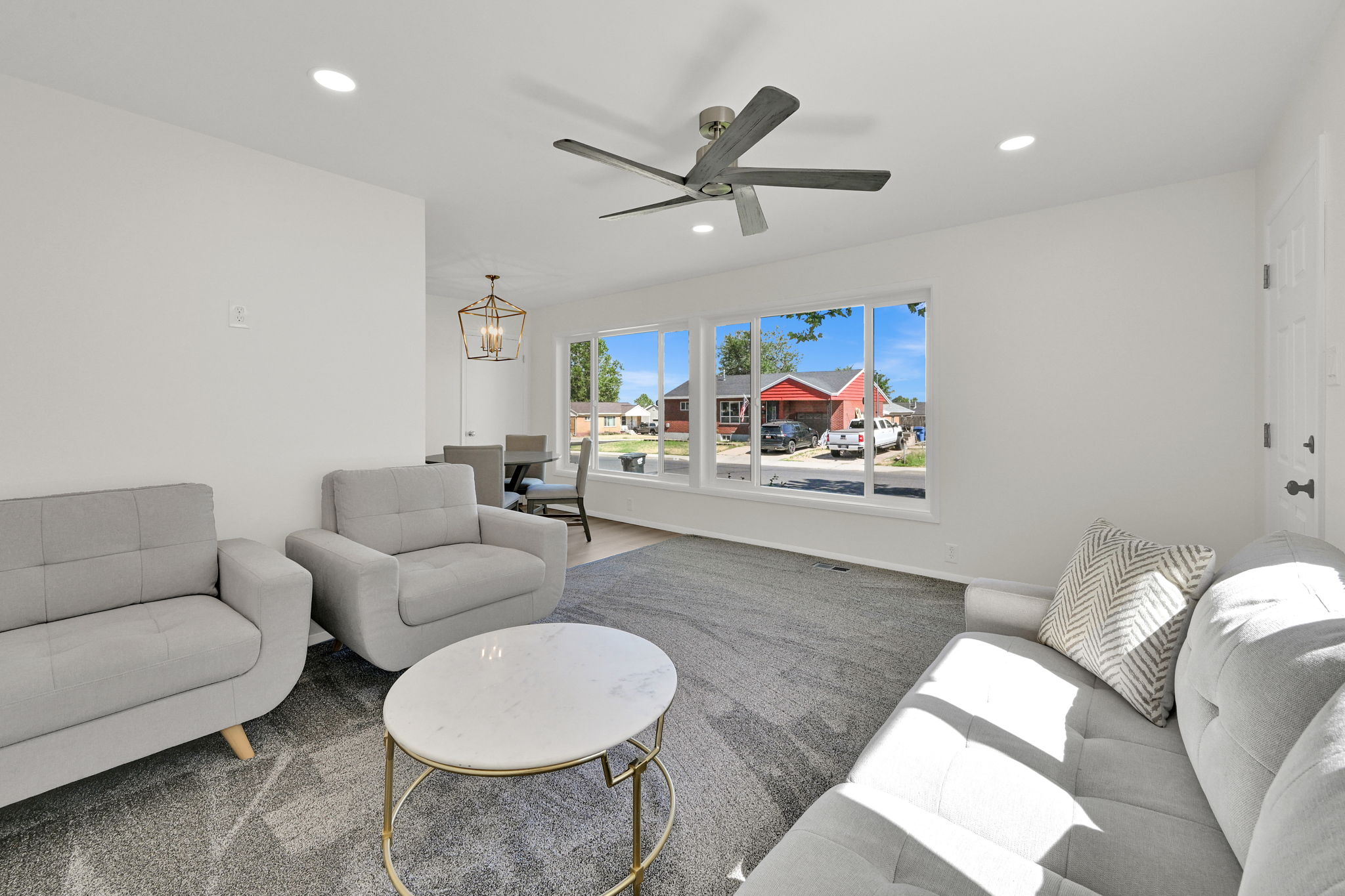 Open-concept living space featuring a modern ceiling fan, recessed lighting, and large picture windows