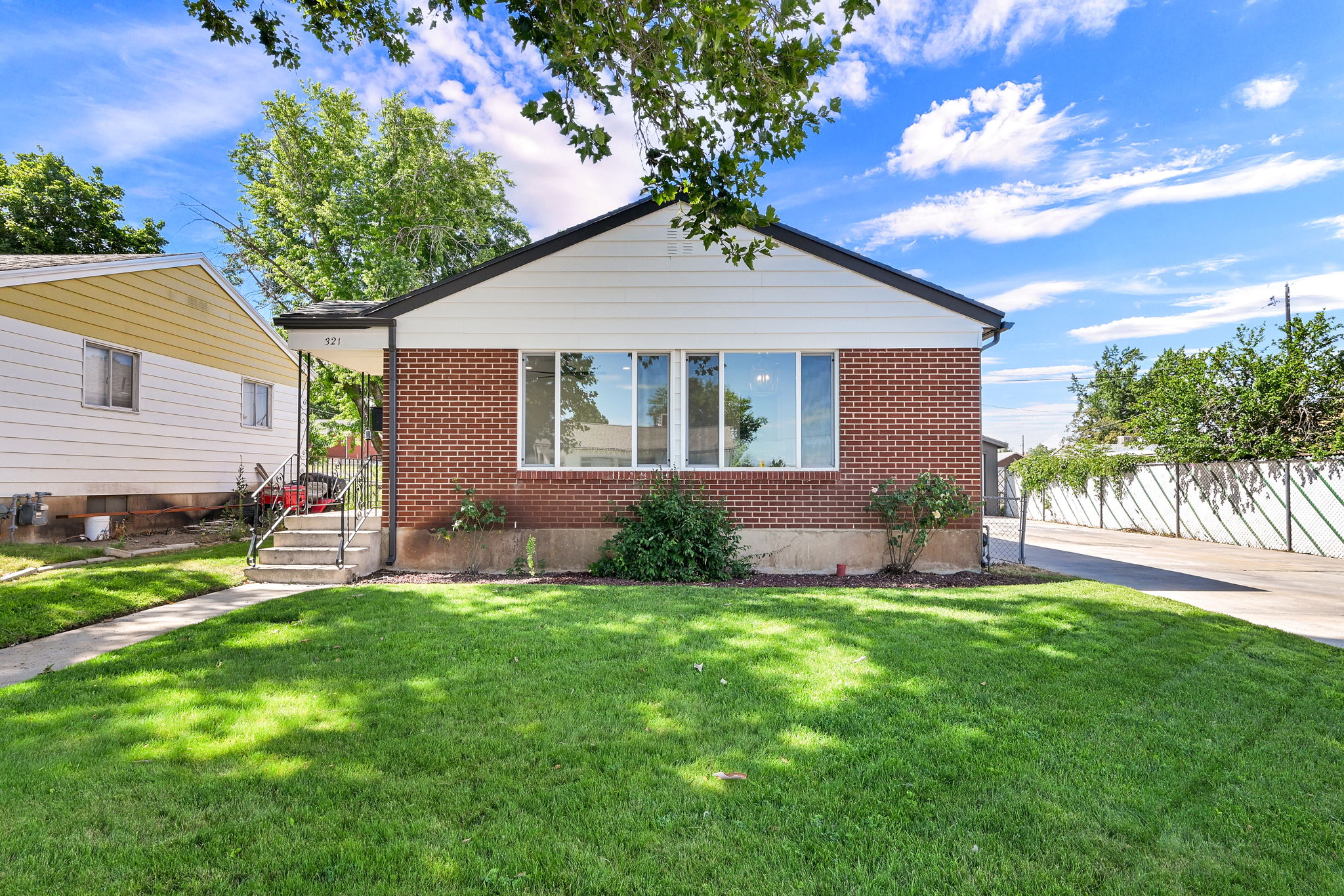 Brick and white siding exterior featuring a multi-pane front window and a concrete walkway