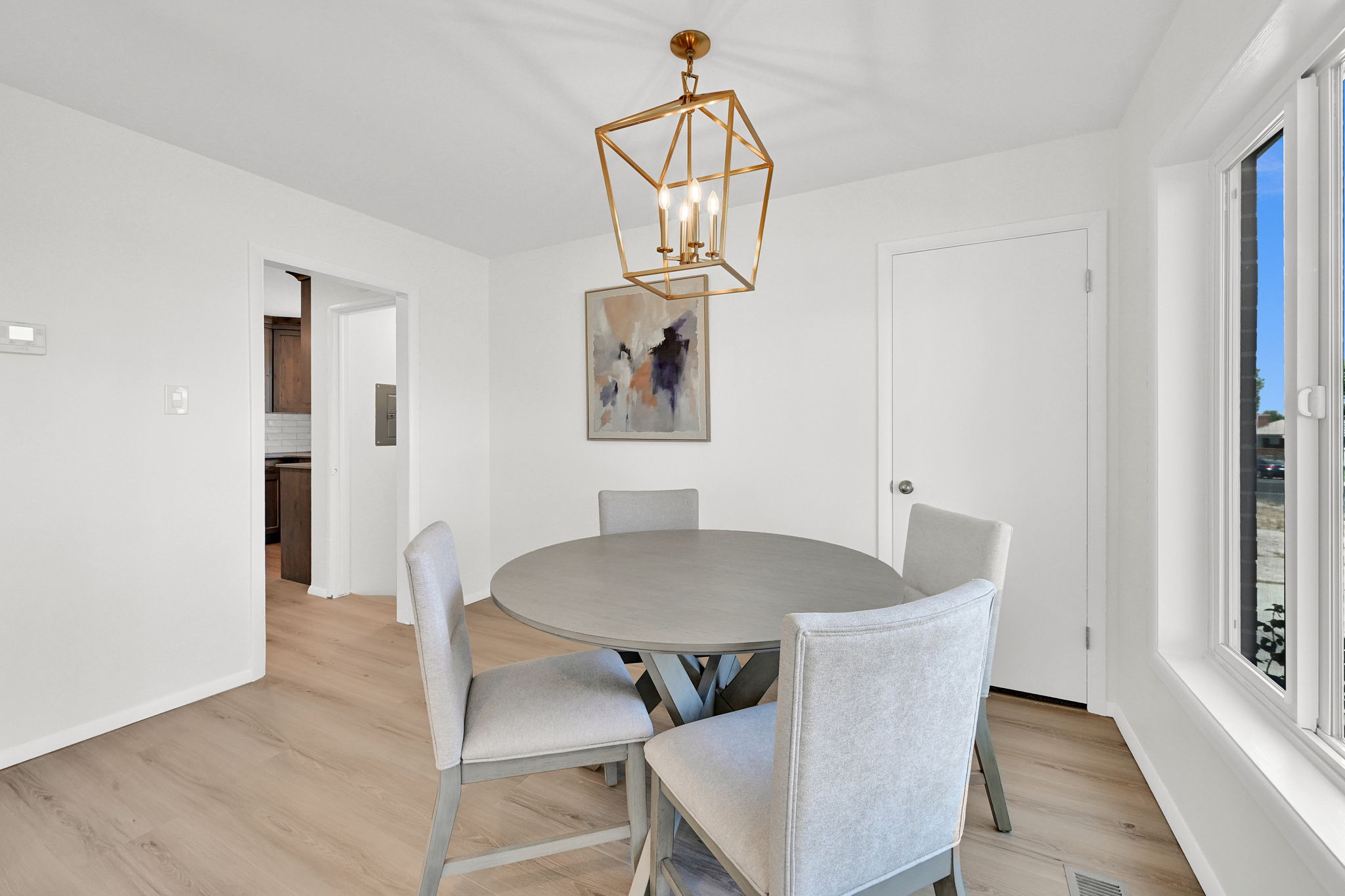 Dining area featuring light wood-finish flooring and a contemporary brass chandelier