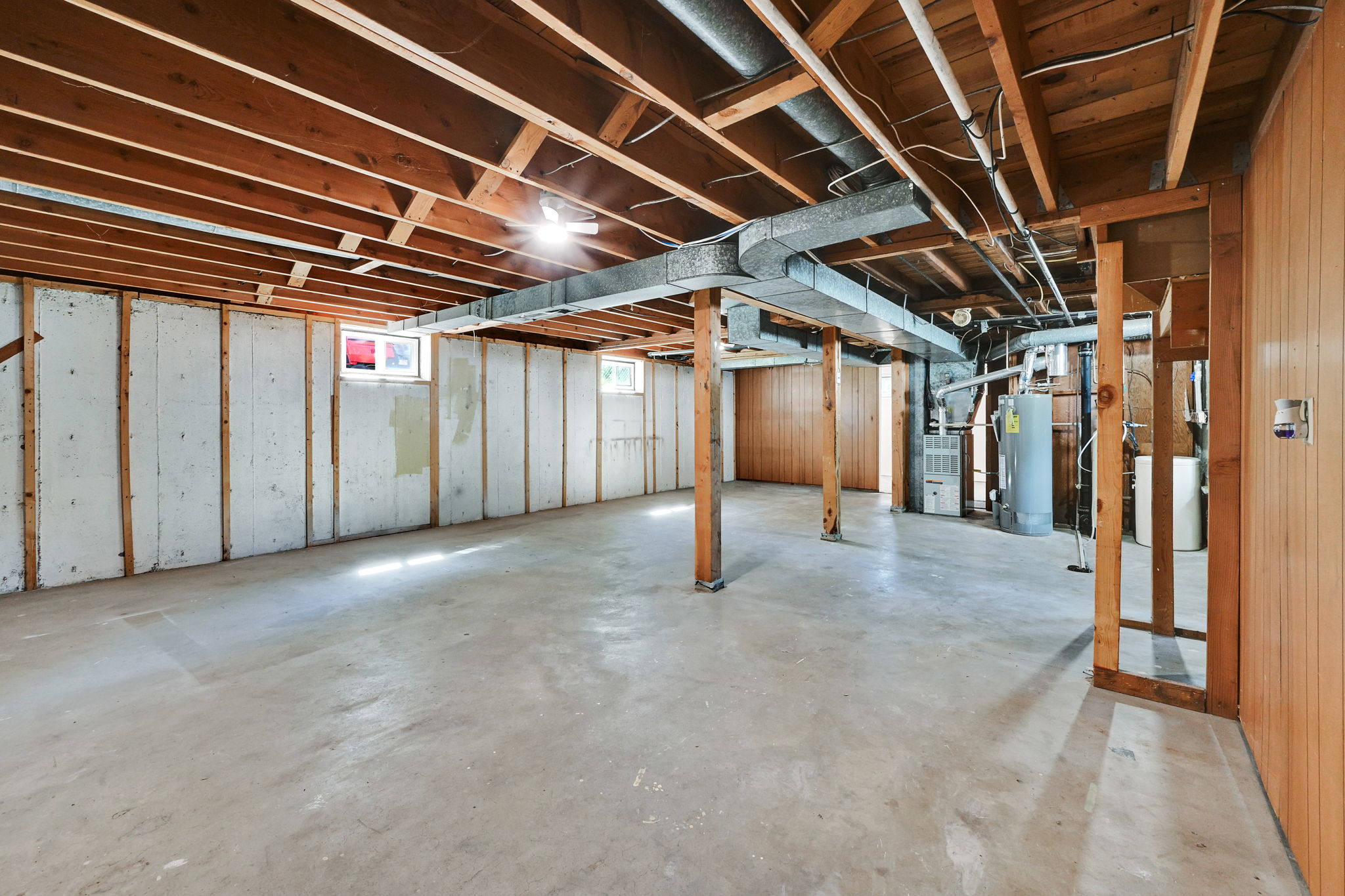 Spacious unfinished basement with exposed wood joists and concrete flooring