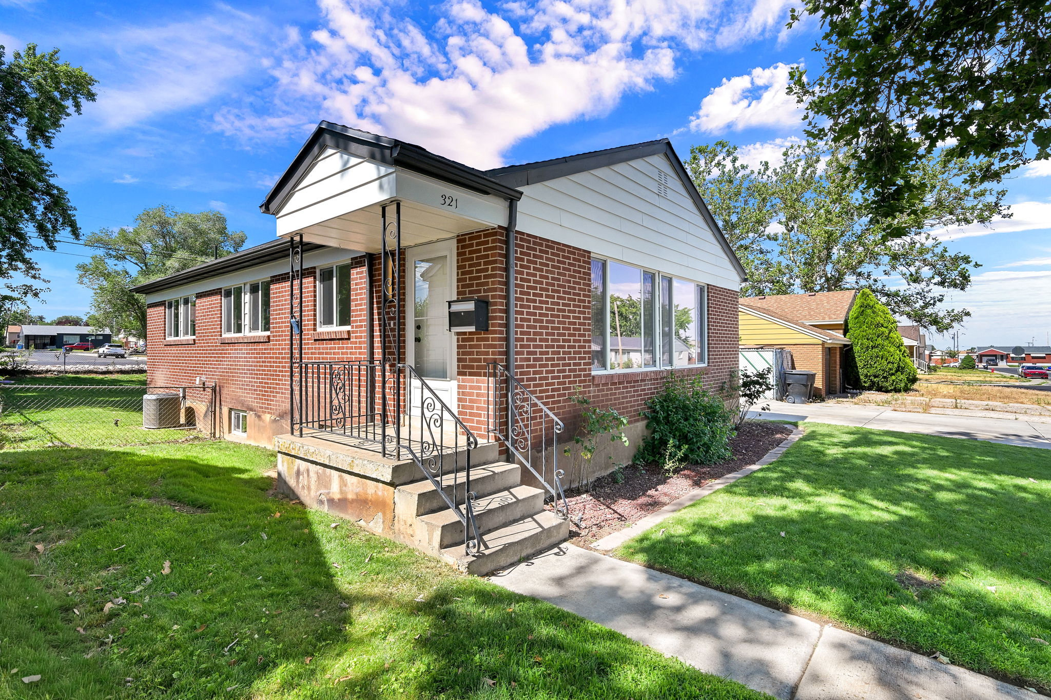 Brick exterior with white siding accents and a covered front porch featuring wrought iron railings