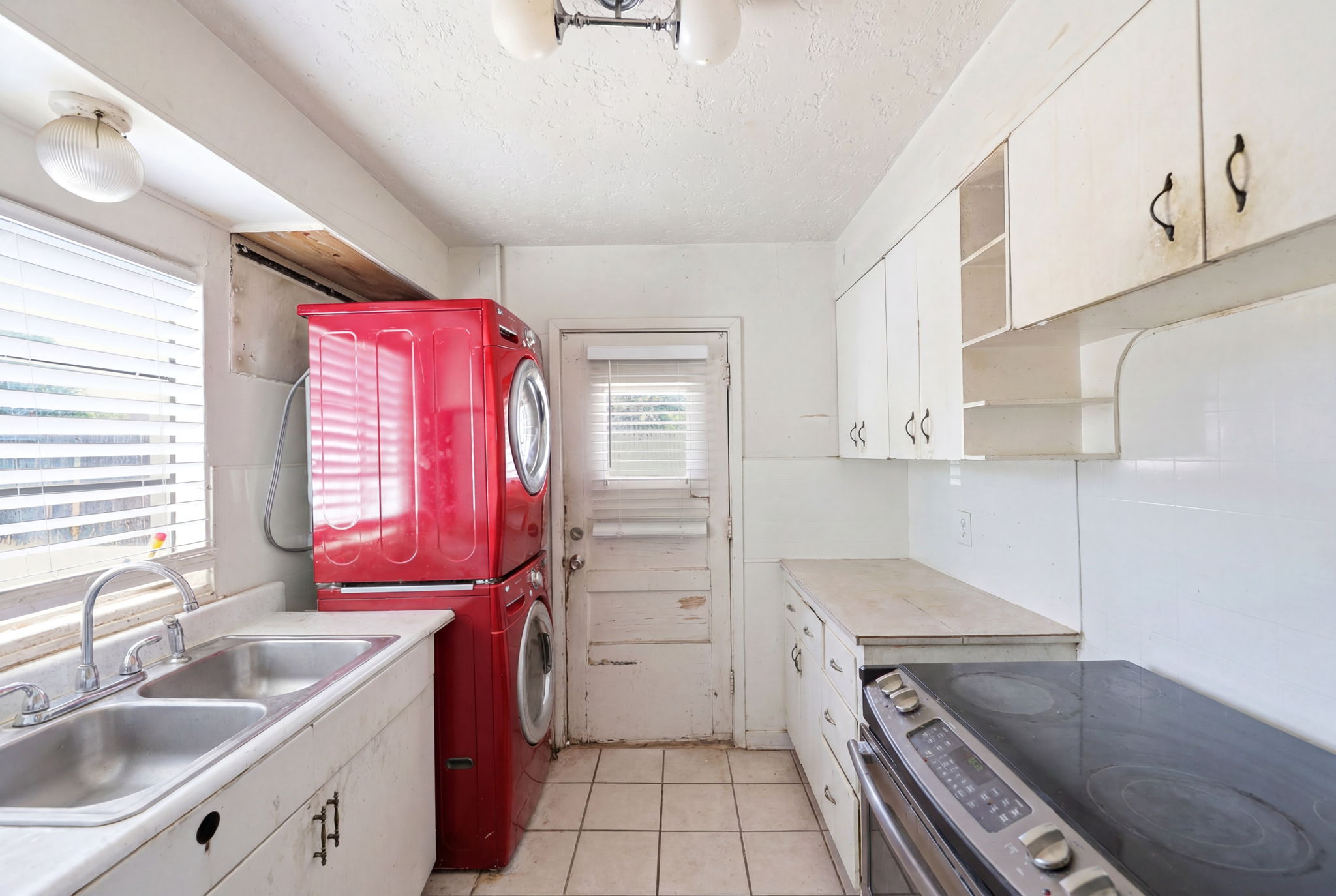 Kitchen space featuring white cabinetry, a double basin stainless steel sink, and a built-in electric range with a flat cooktop