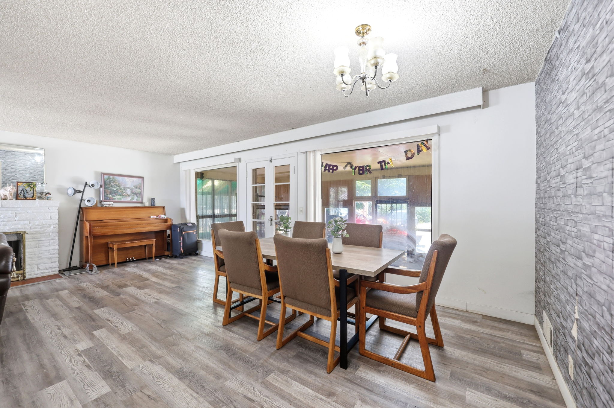 Spacious dining area featuring wood-finish flooring and a stone accent wall