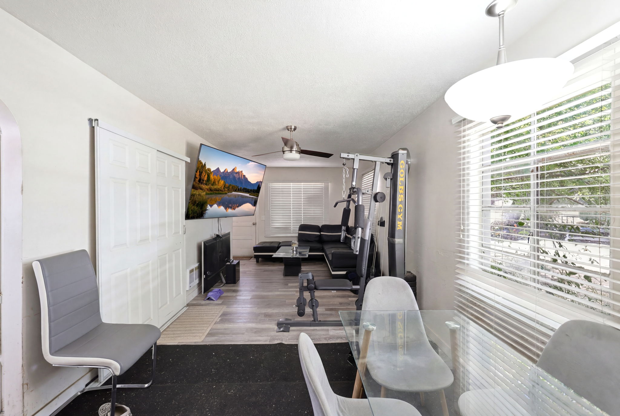 Open concept room featuring wood-finish flooring, white walls, and a ceiling fan