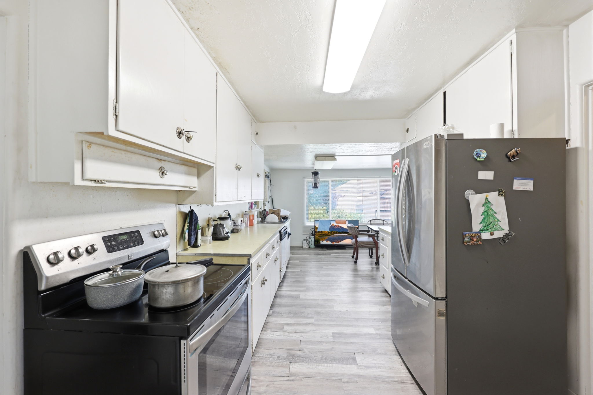 Galley kitchen featuring white cabinetry, light-toned countertops, and wood-finish flooring
