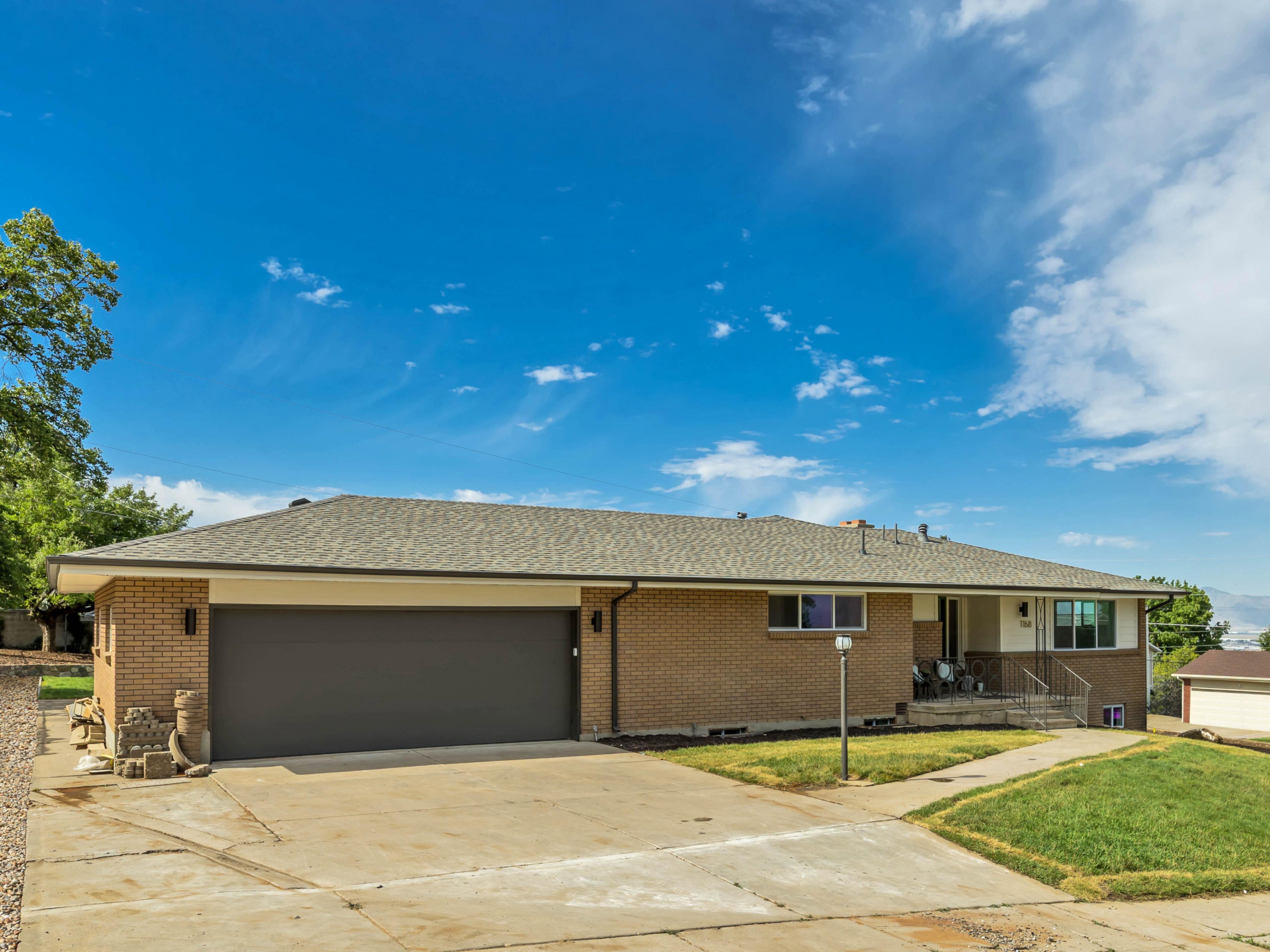 Brick exterior featuring a two-car garage, concrete driveway, and covered front entry