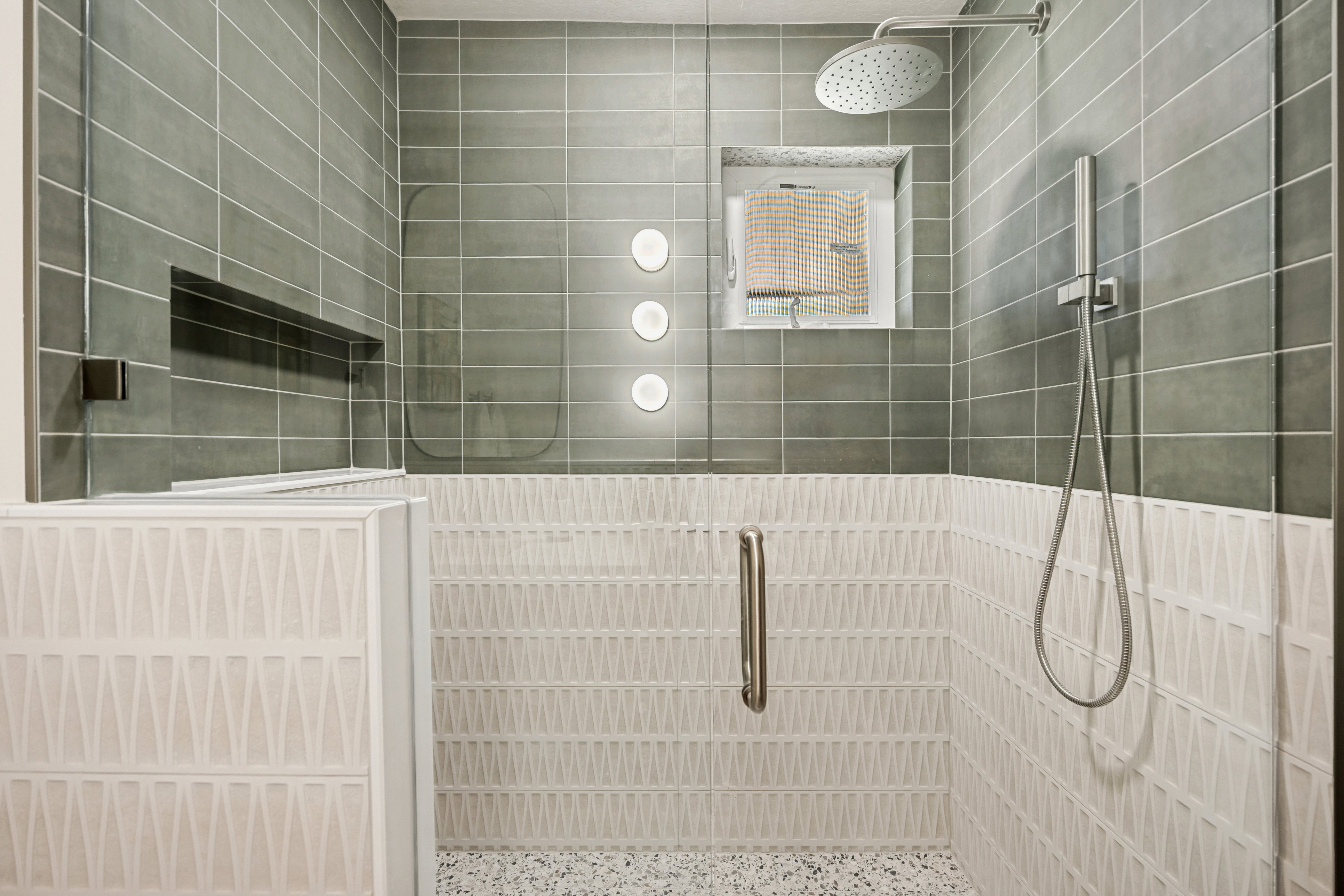Walk-in shower featuring a rain shower head, handheld shower fixture, and a built-in niche