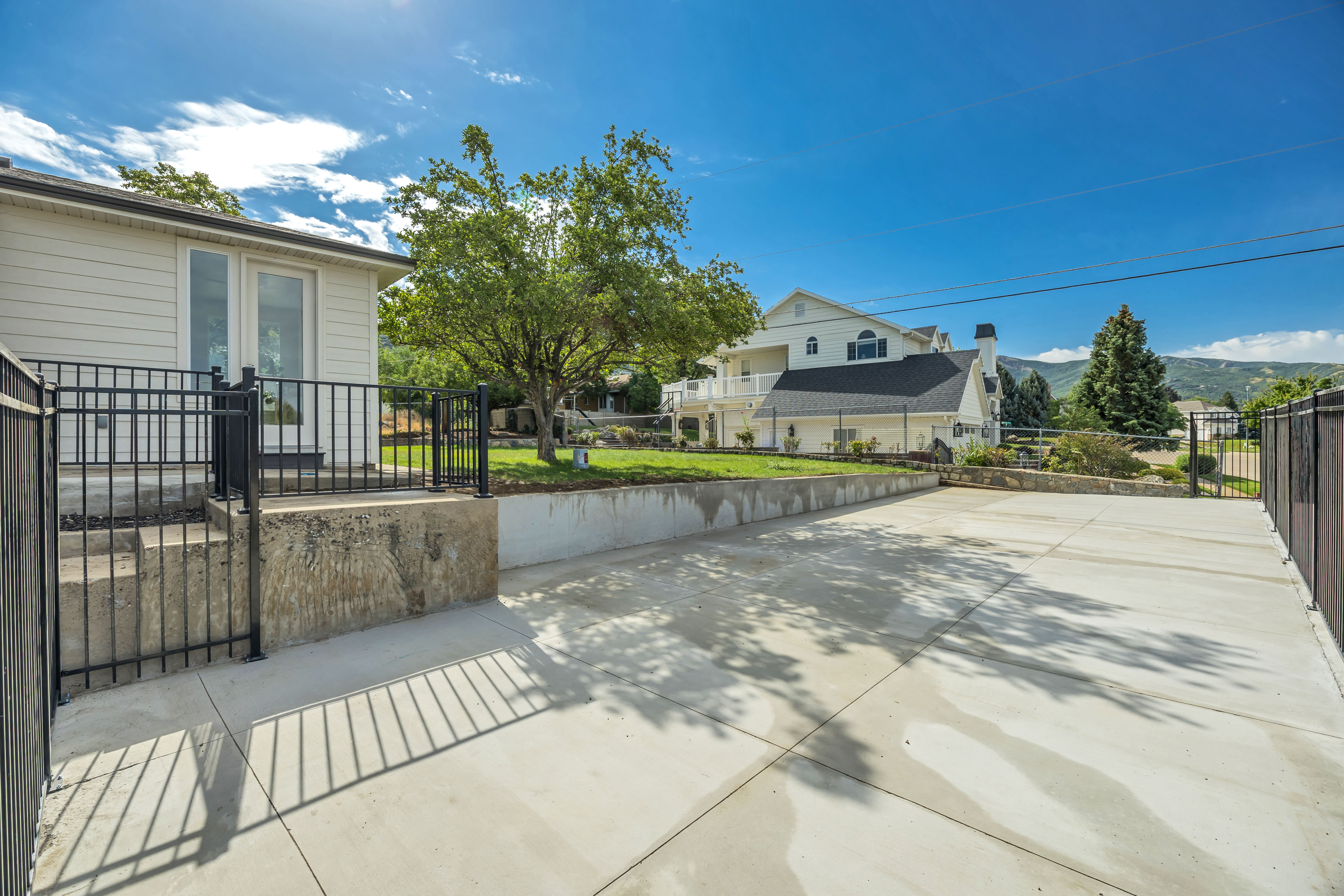 Expansive concrete driveway framed by black metal fencing