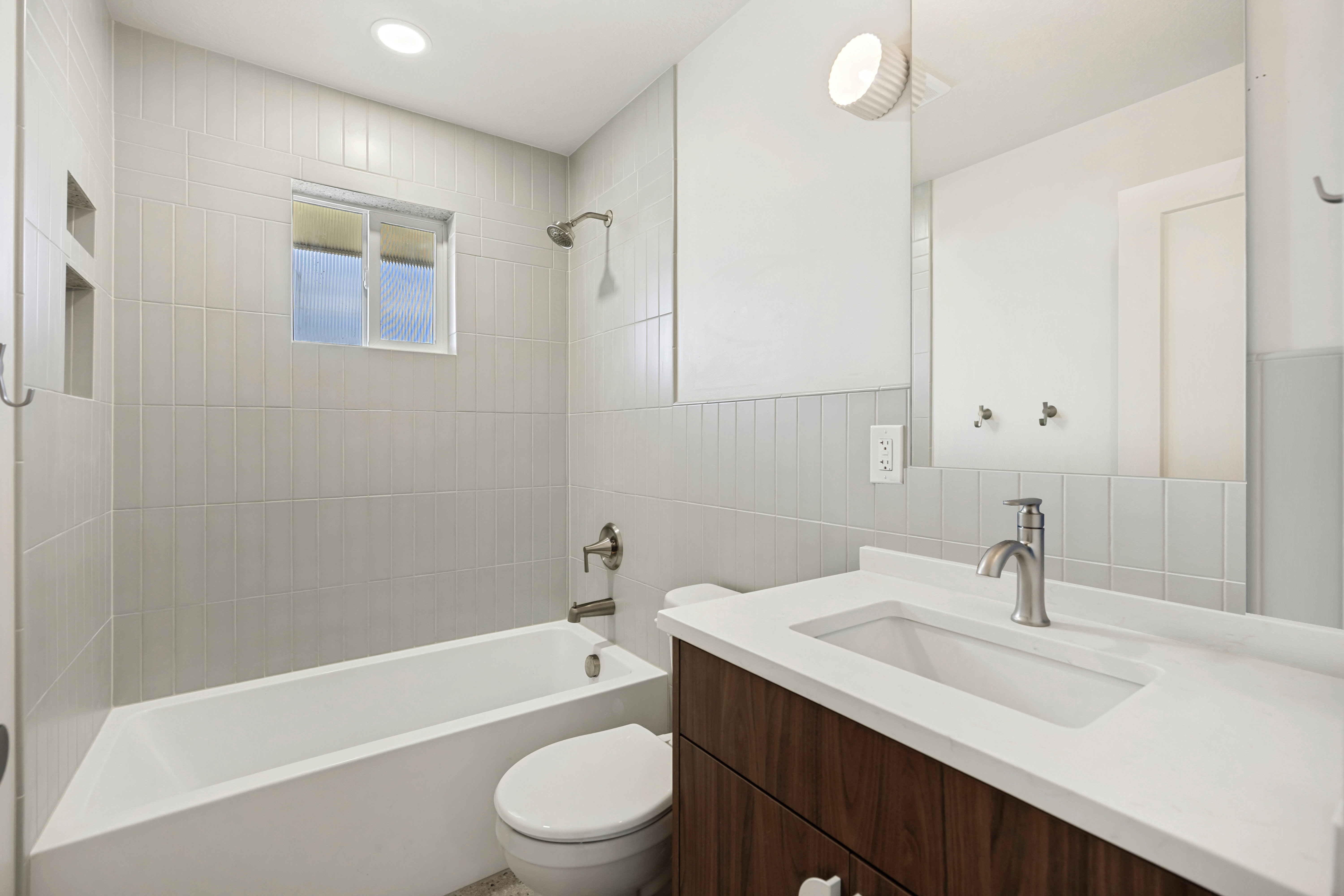Bathroom featuring a wood-finish vanity with an integrated white sink, brushed nickel faucet, and a large wall-mounted mirror