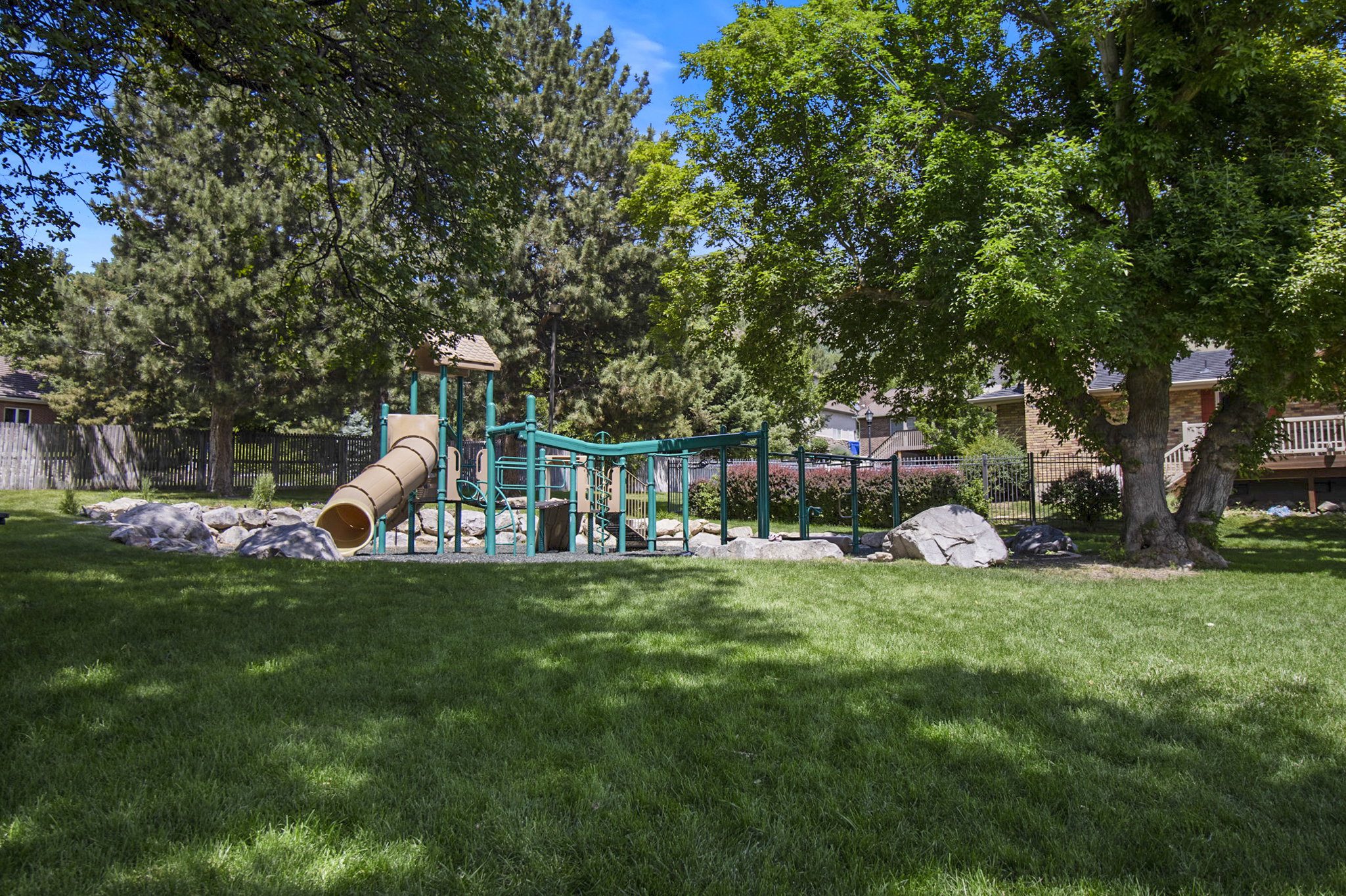 Expansive green lawn featuring a built-in playground structure with a tube slide, multiple platforms, and climbing elements