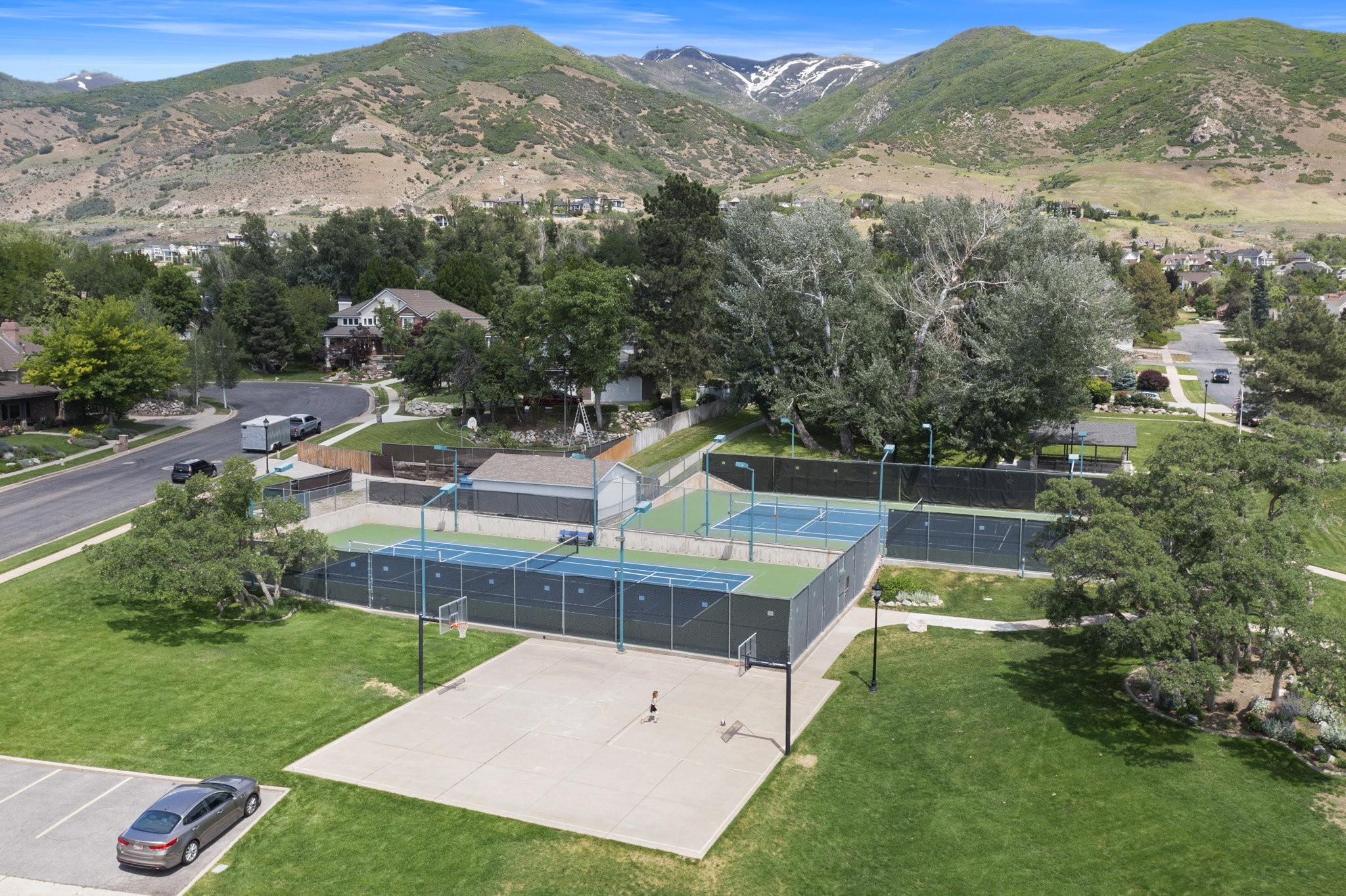 Community athletic courts featuring multiple tennis courts, a basketball court, and surrounding green spaces