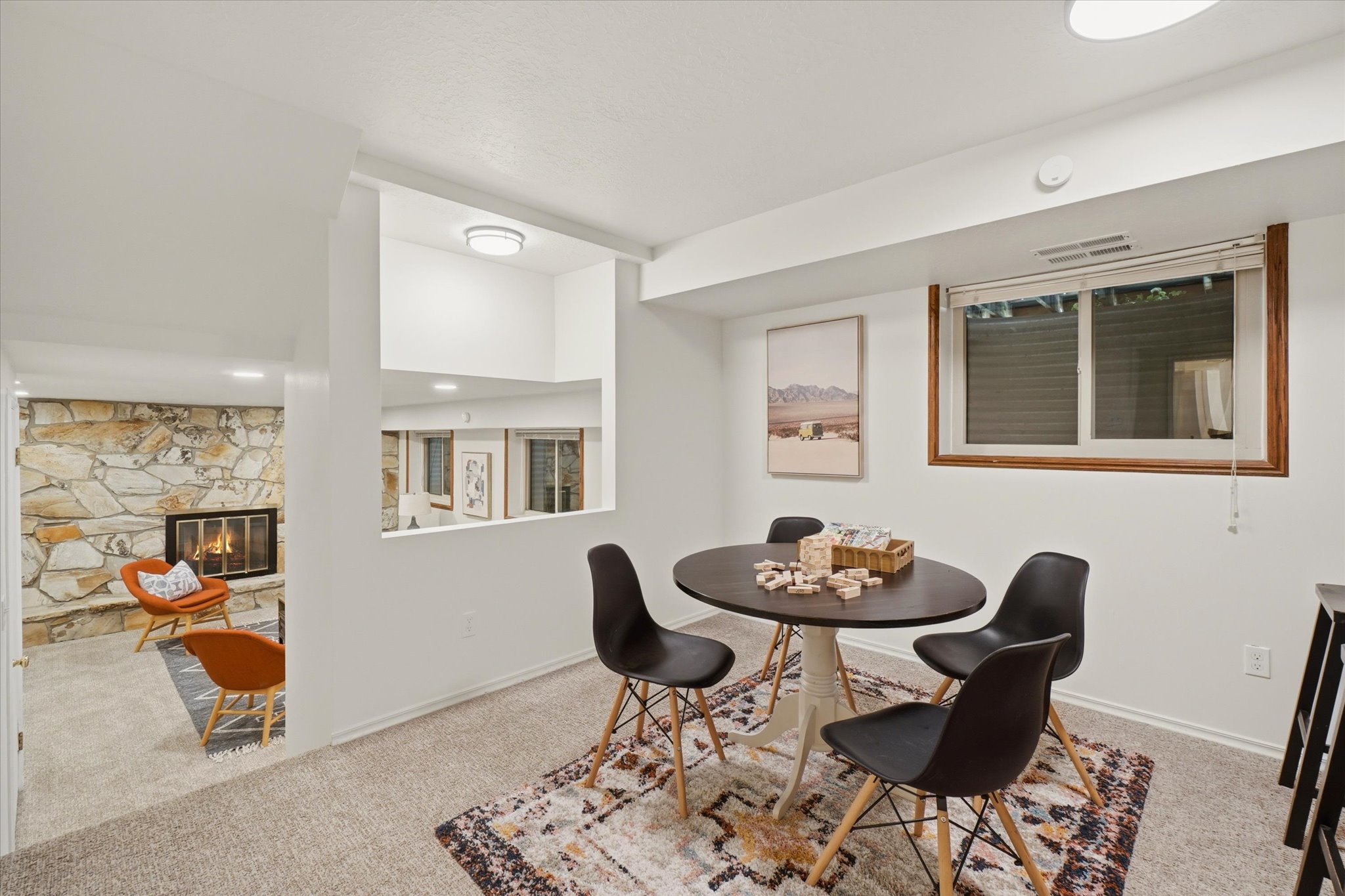 Carpeted recreation room featuring a pass-through window to an additional living space, recessed lighting, and a wood-framed window