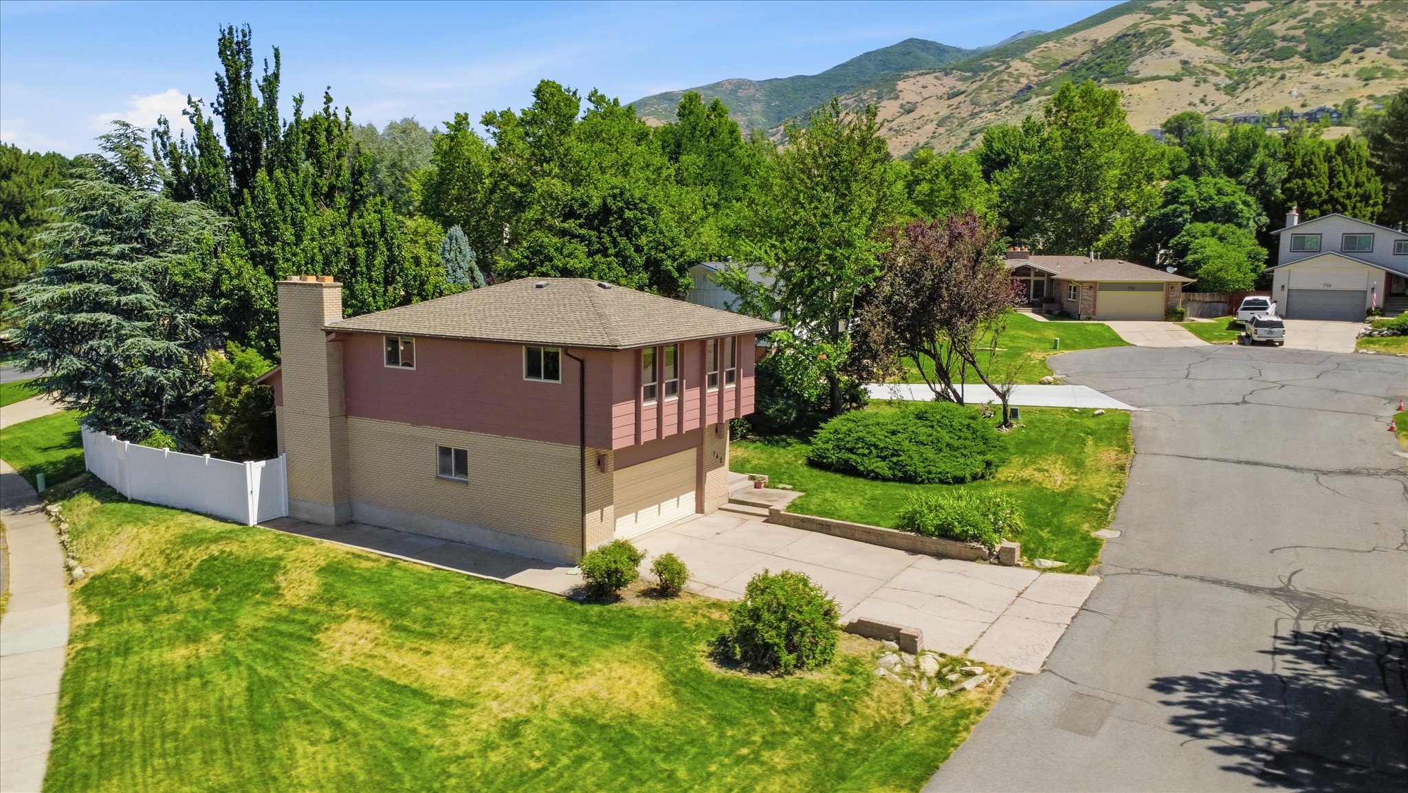 Split-level residence featuring a two-car garage and a stone chimney
