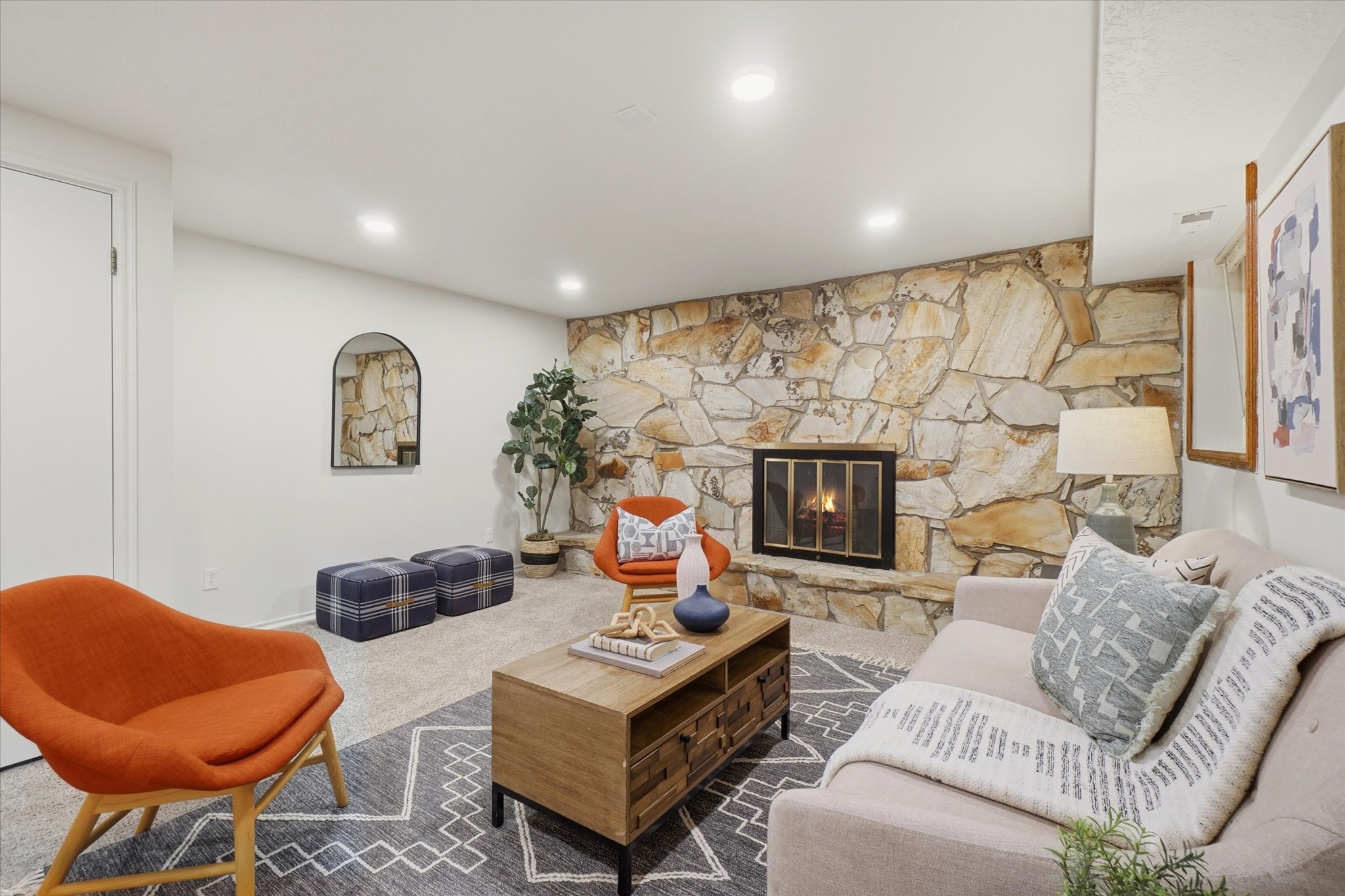 Living area featuring a stone accent wall with a built-in fireplace, recessed lighting, and light-toned carpeting