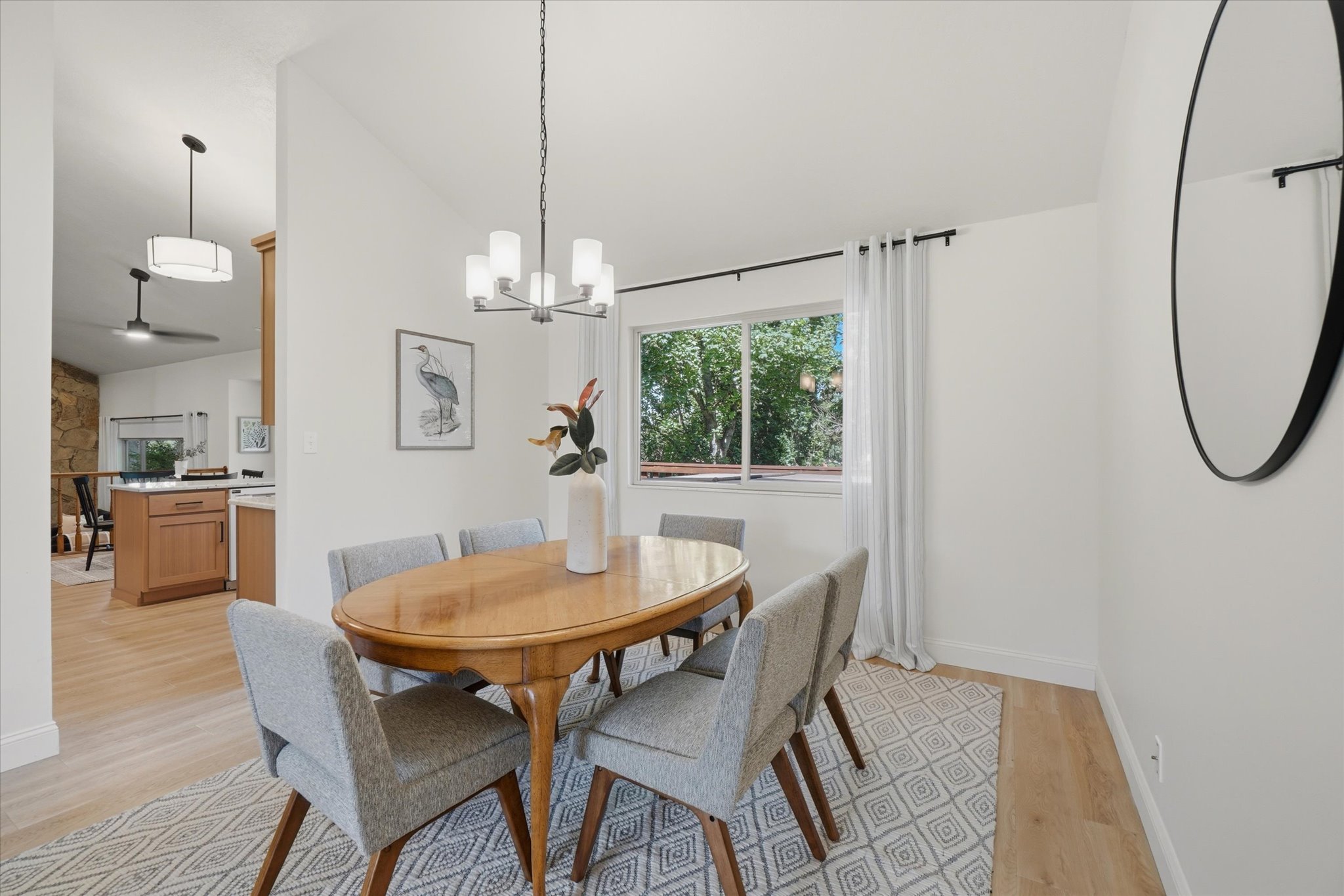 Bright dining area featuring a contemporary chandelier, wood-finish flooring, and a large window