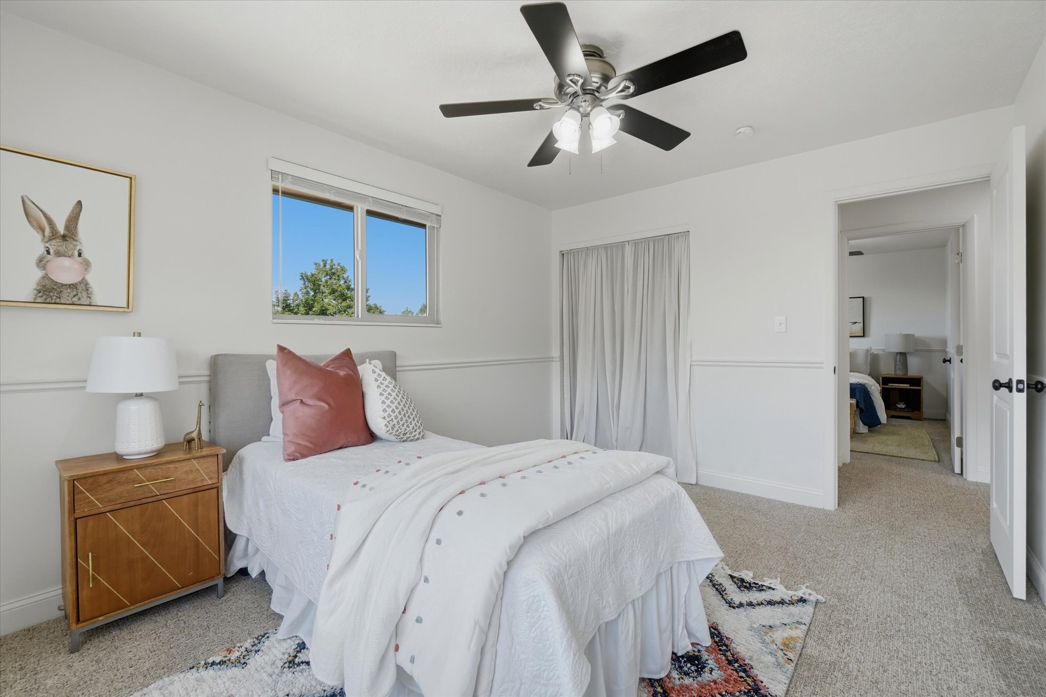 Bedroom featuring light gray carpeting, crisp white walls, and a recessed window