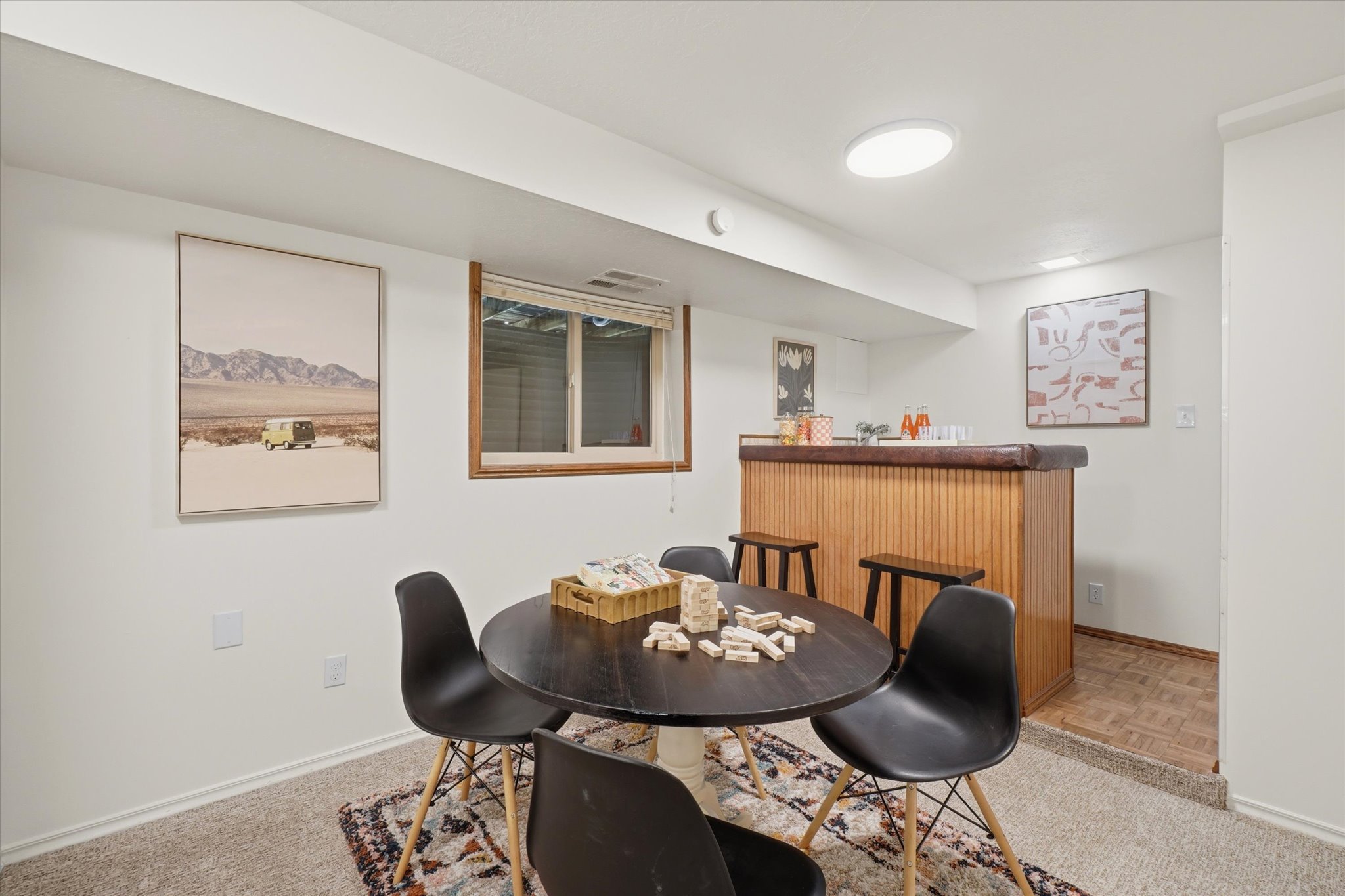Lower-level recreation space featuring carpet flooring and a built-in bar with wood paneling