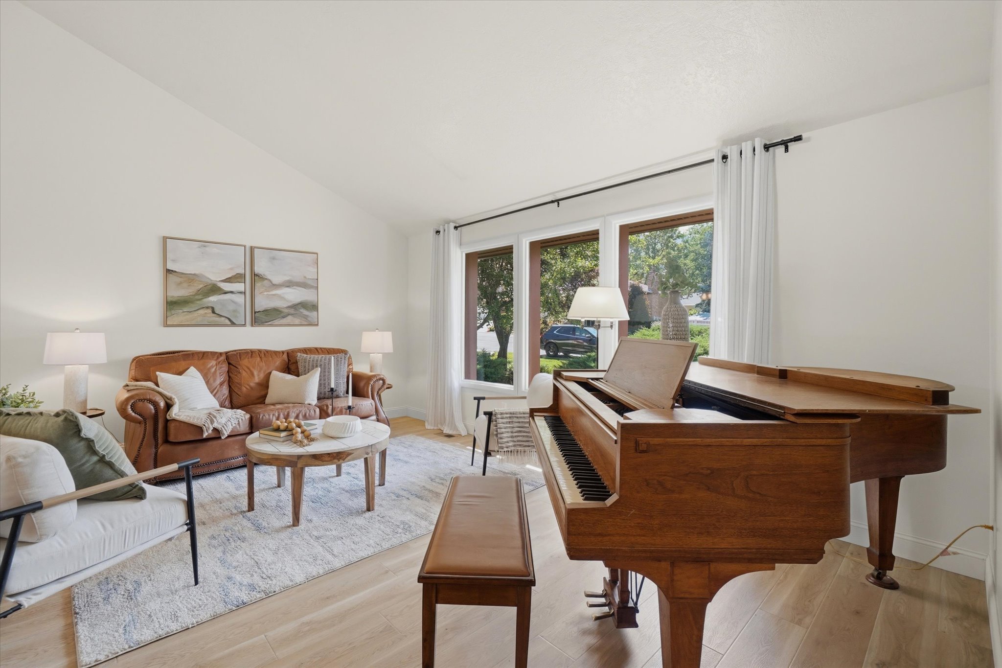 Bright interior space featuring a grand piano, light wood-finish flooring, and expansive windows