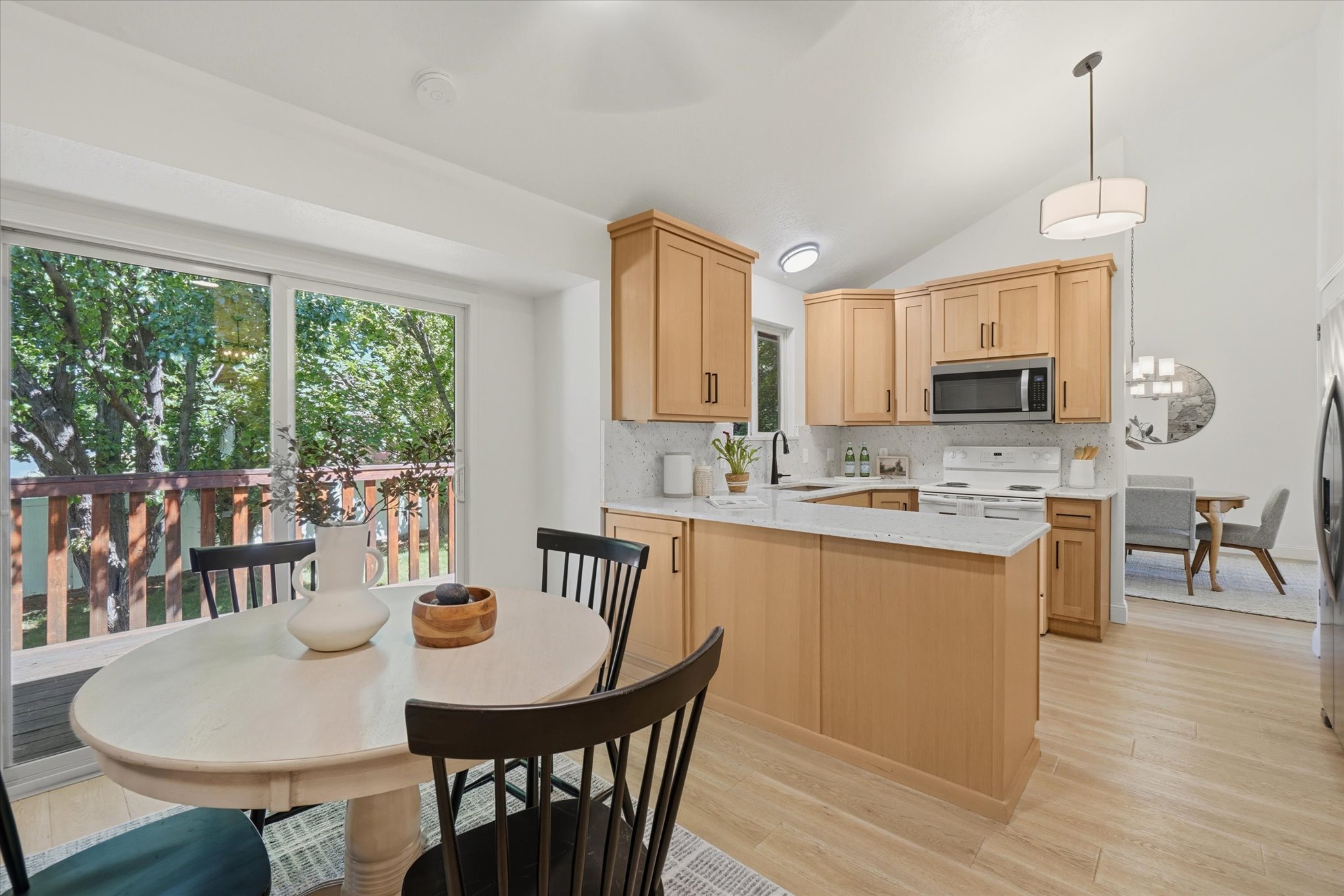 Kitchen featuring light wood cabinetry, white stone countertops, stainless steel appliances, and a mosaic tile backsplash