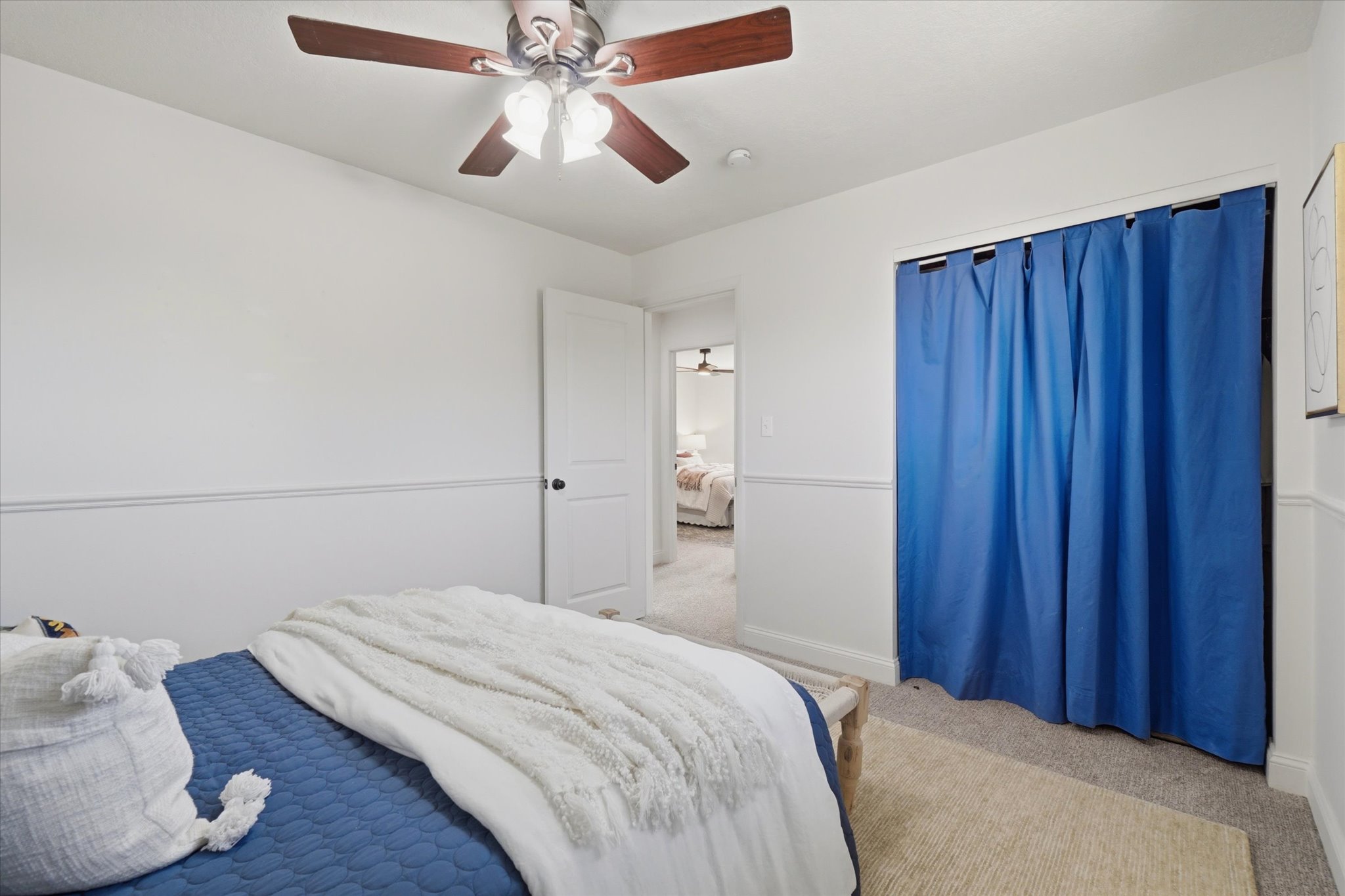 Room featuring a ceiling fan with wooden blades, wall molding, and neutral carpeting