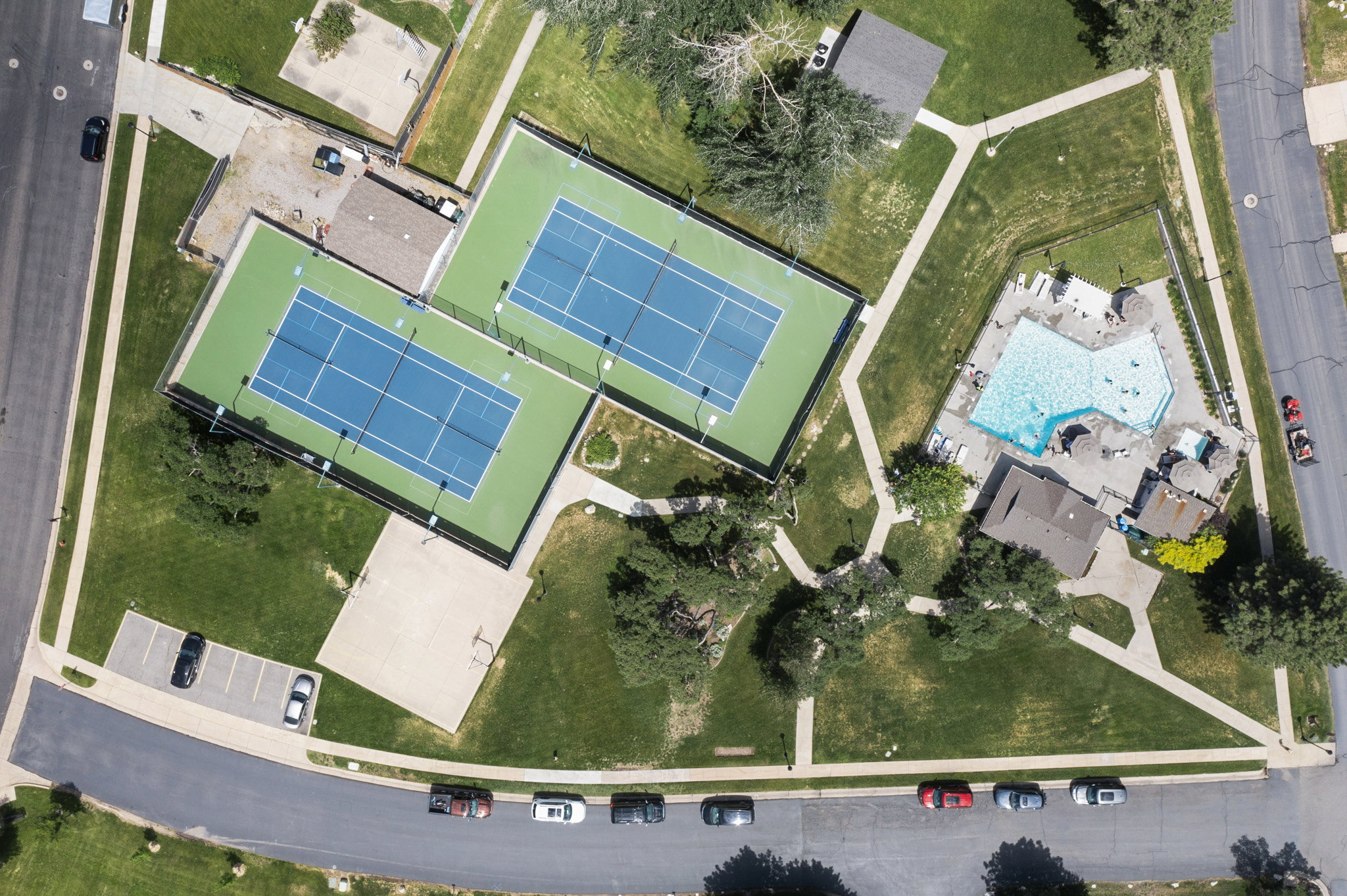 Community recreation area featuring two tennis courts, an irregularly shaped swimming pool, and dedicated parking