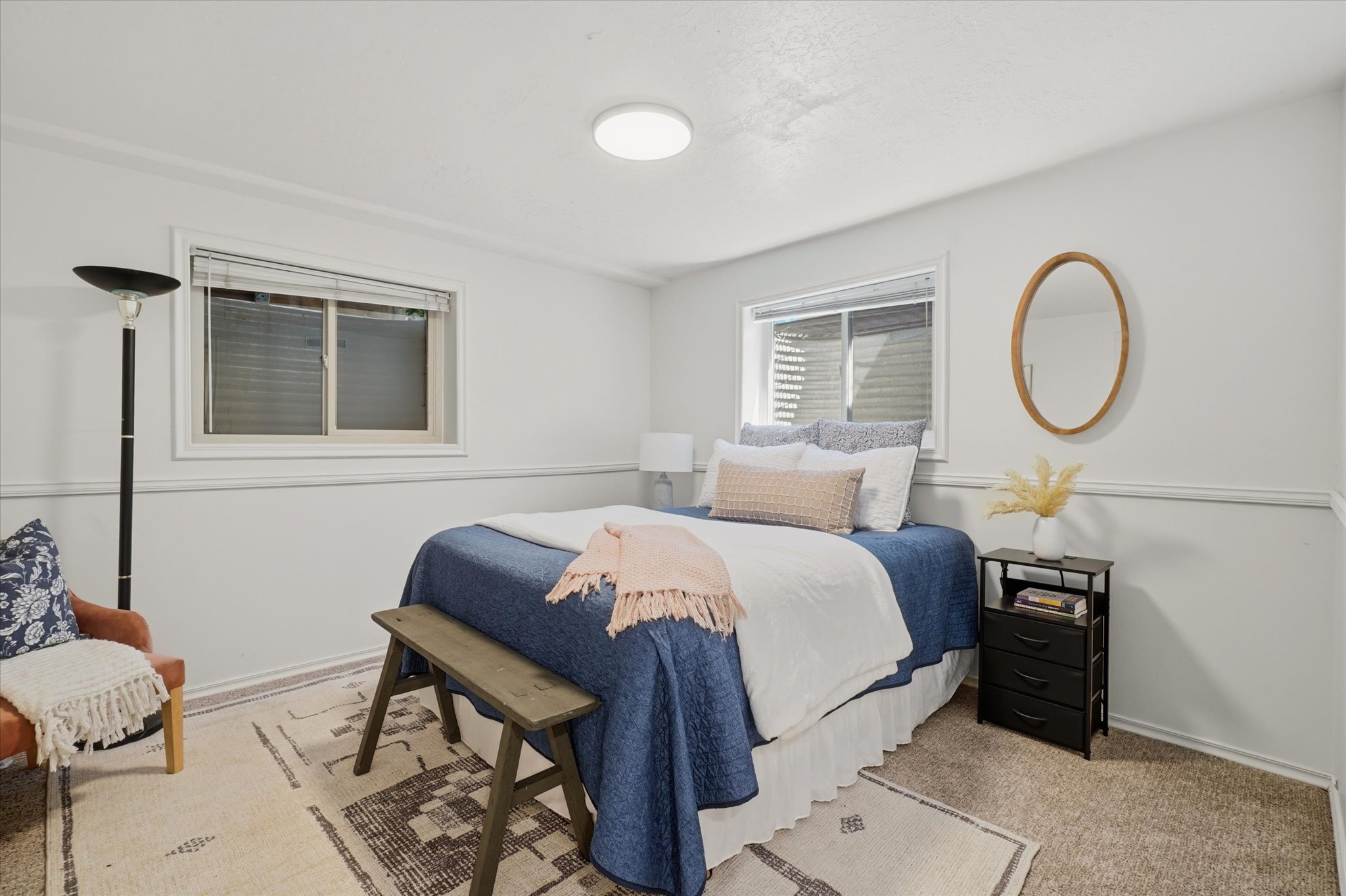 Bedroom with two windows, light gray walls, white trim, and neutral-toned carpeting