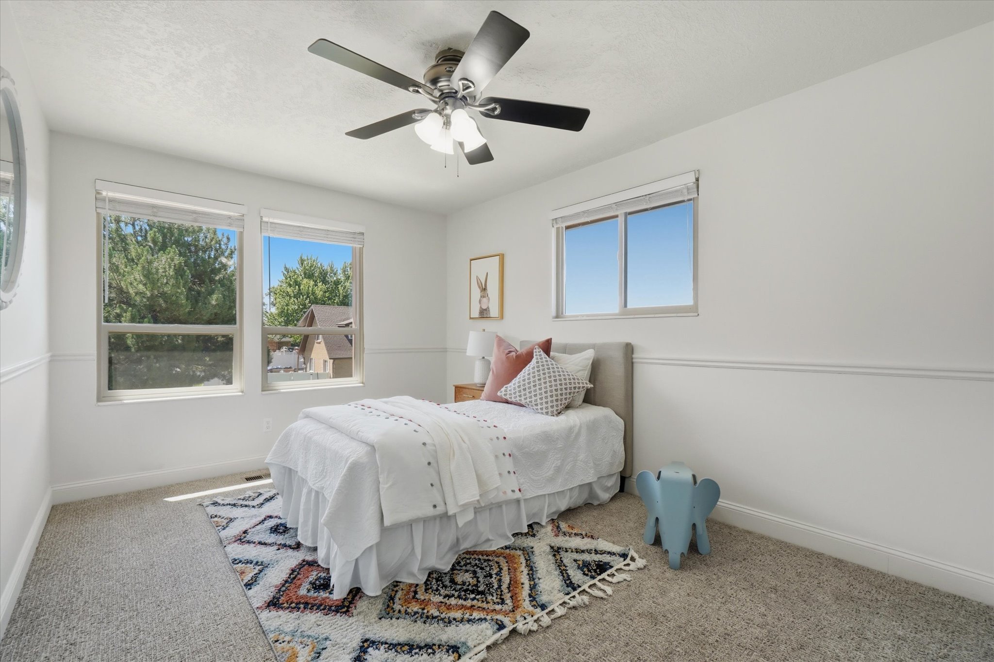 Interior room featuring two large windows, a single smaller window, a ceiling fan with integrated lighting, wall molding, and carpet flooring