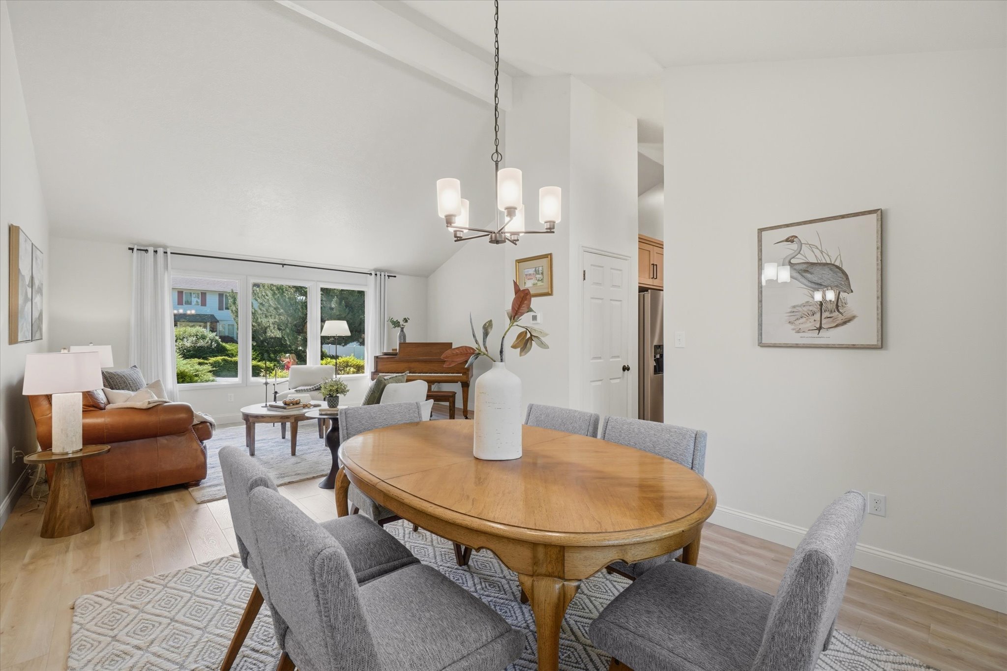 Open-concept dining area featuring wood-finish flooring, a contemporary chandelier, and a vaulted ceiling