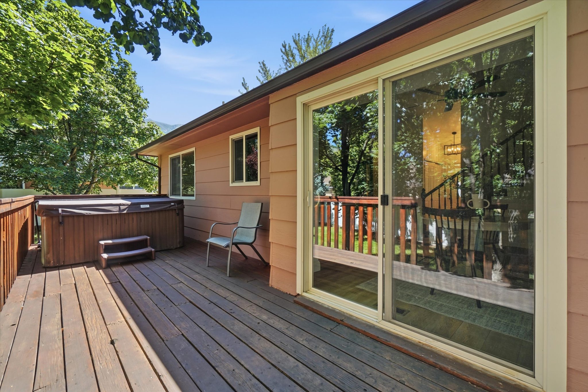 Expansive outdoor deck featuring a built-in hot tub, durable wood decking, and a sliding glass door for interior access