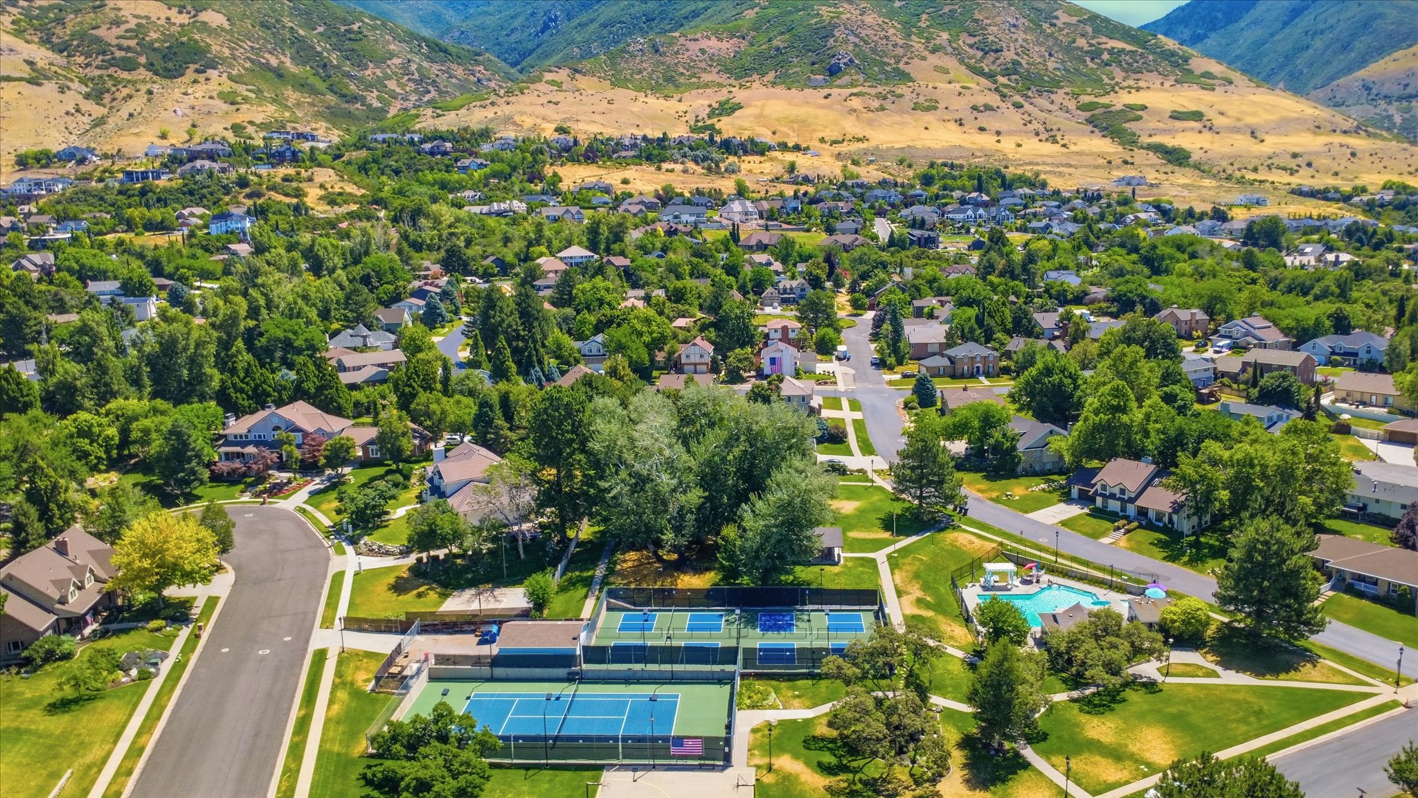 Aerial view of the neighborhood pool, pickleball/tennis courts, playground and basketball court.