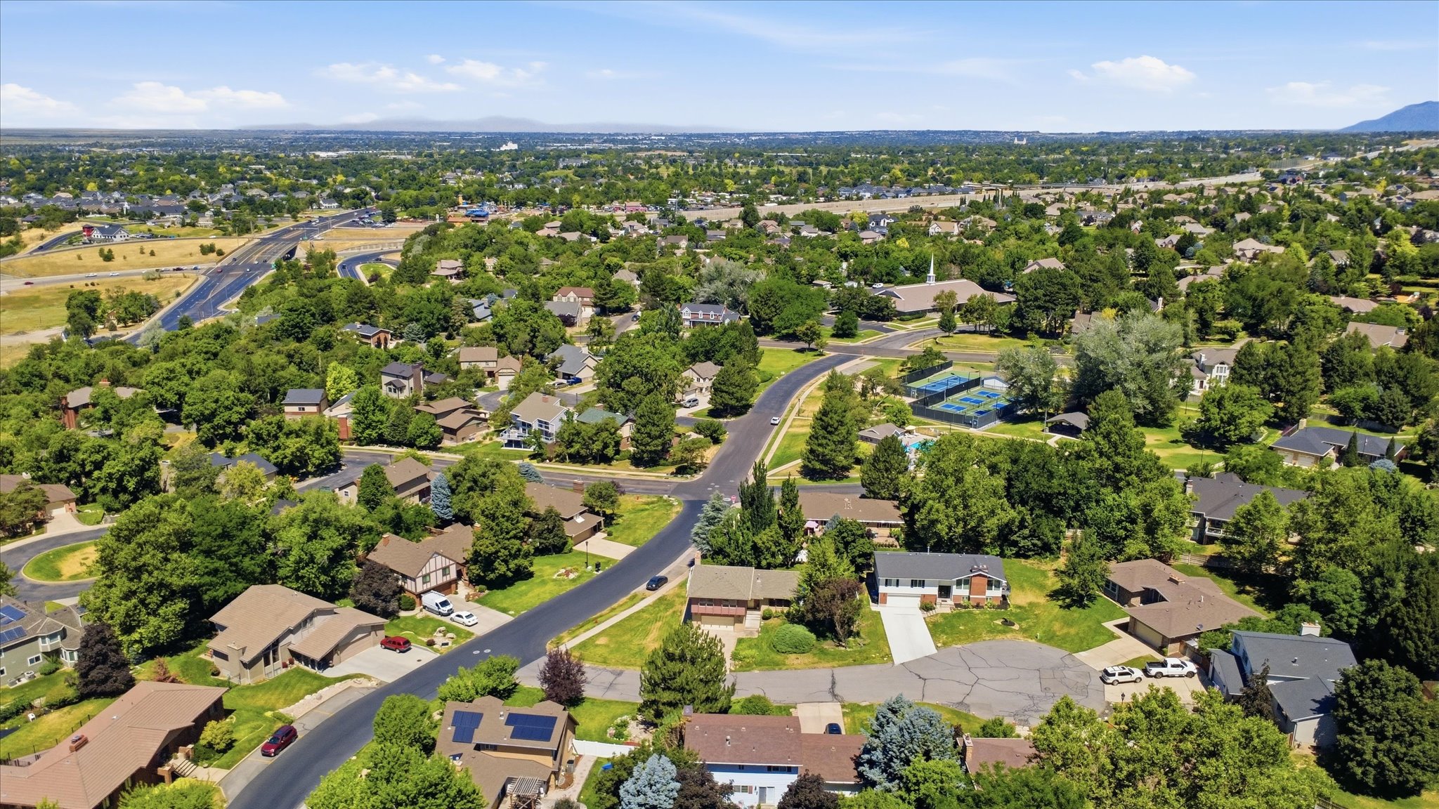 Expansive aerial view showcasing a residential neighborhood with established trees, winding streets, and a variety of architectural styles