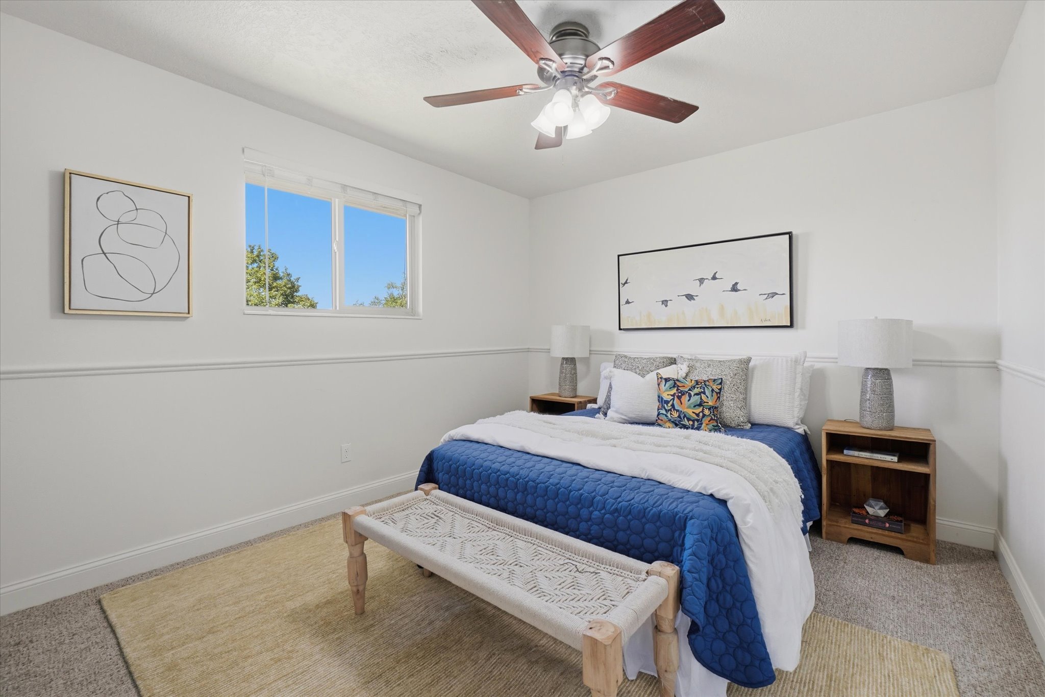 Bedroom featuring white walls with chair rail molding, a ceiling fan with light fixture, and a window providing natural illumination