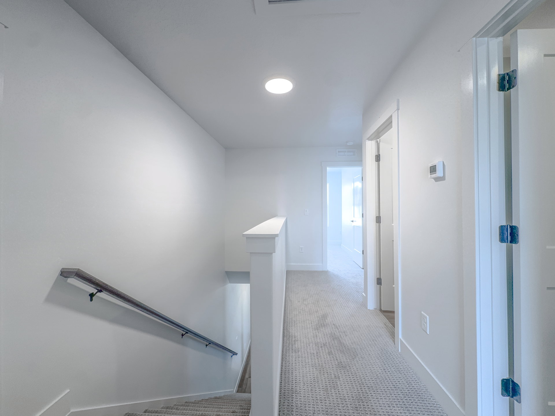 Upper-level hallway featuring light-colored walls and patterned carpet flooring