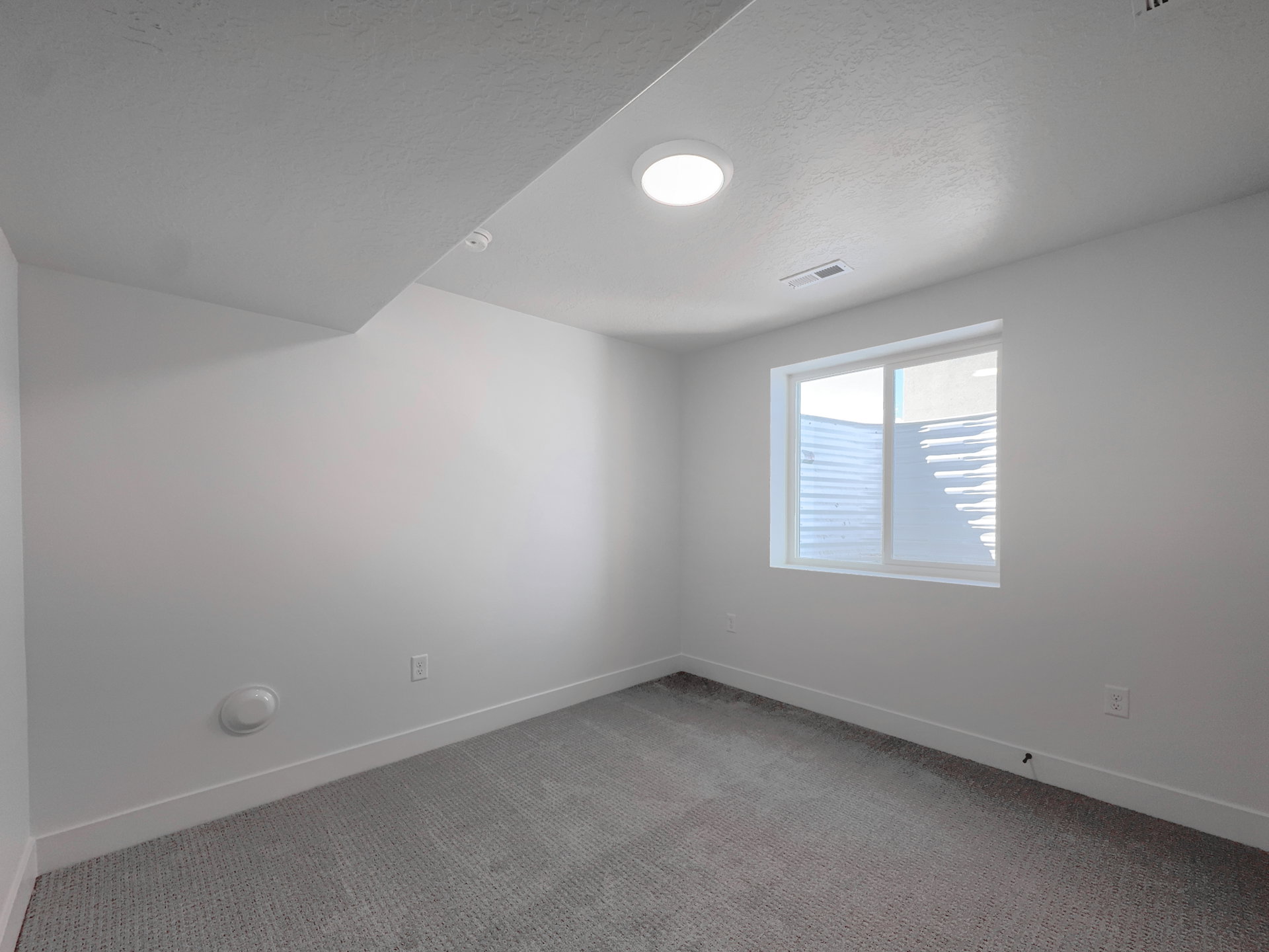 Room featuring a white-framed window, textured carpeting, crisp white walls, and a recessed ceiling light fixture