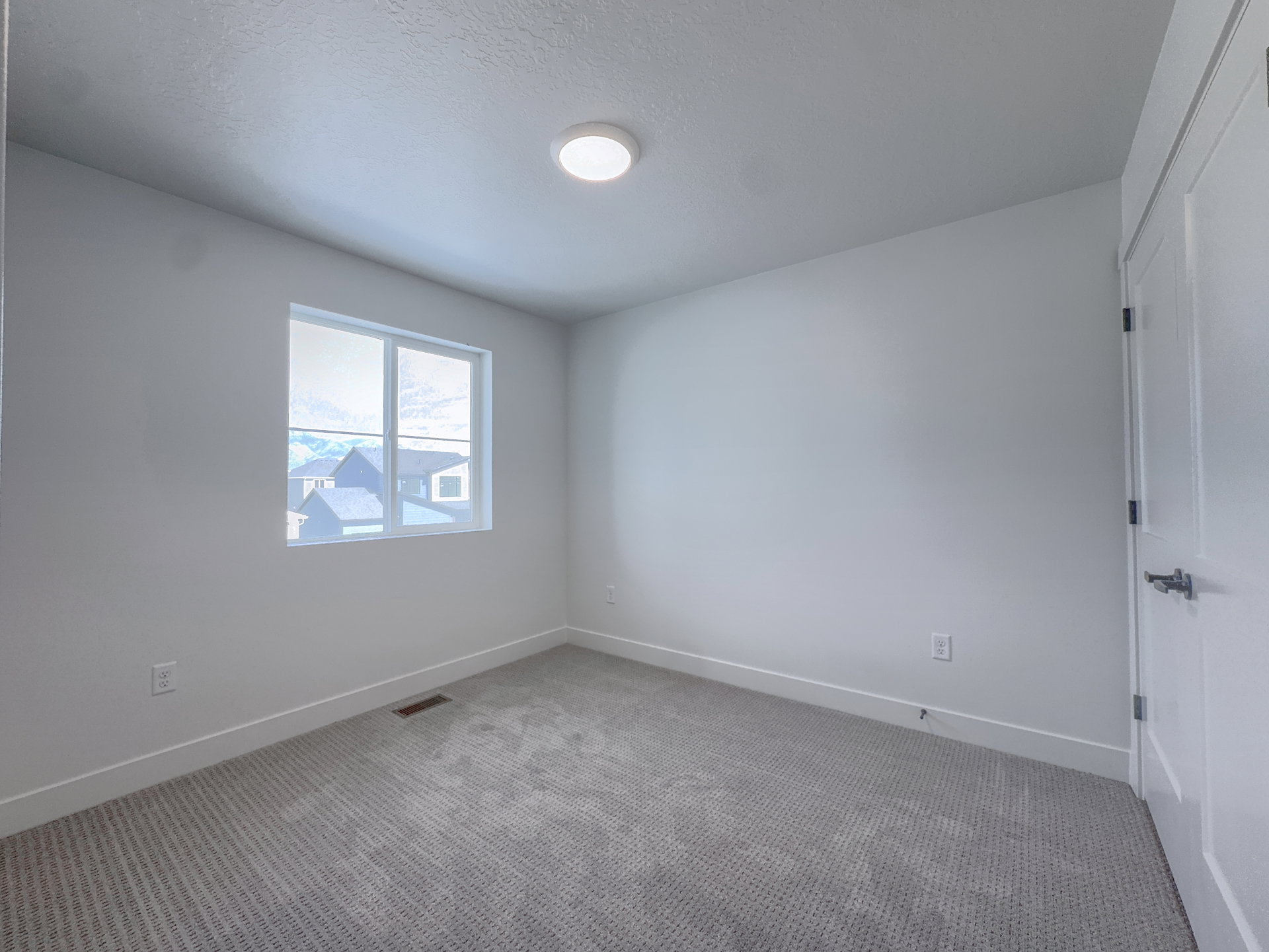 Carpeted room featuring a single window, white baseboards, and a white interior door with dark hardware
