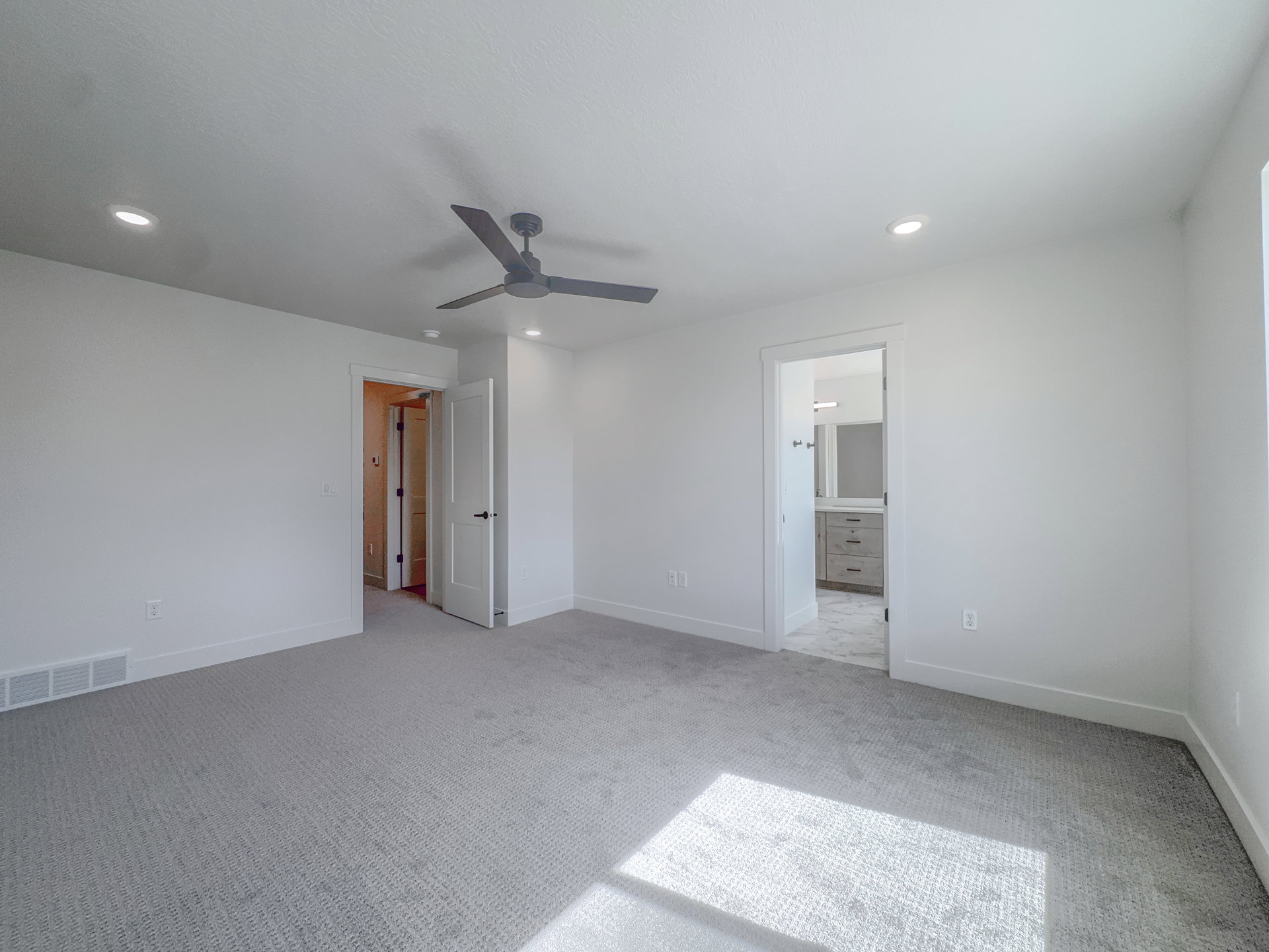 Spacious room featuring light gray carpet, white walls, recessed lighting, and a modern ceiling fan
