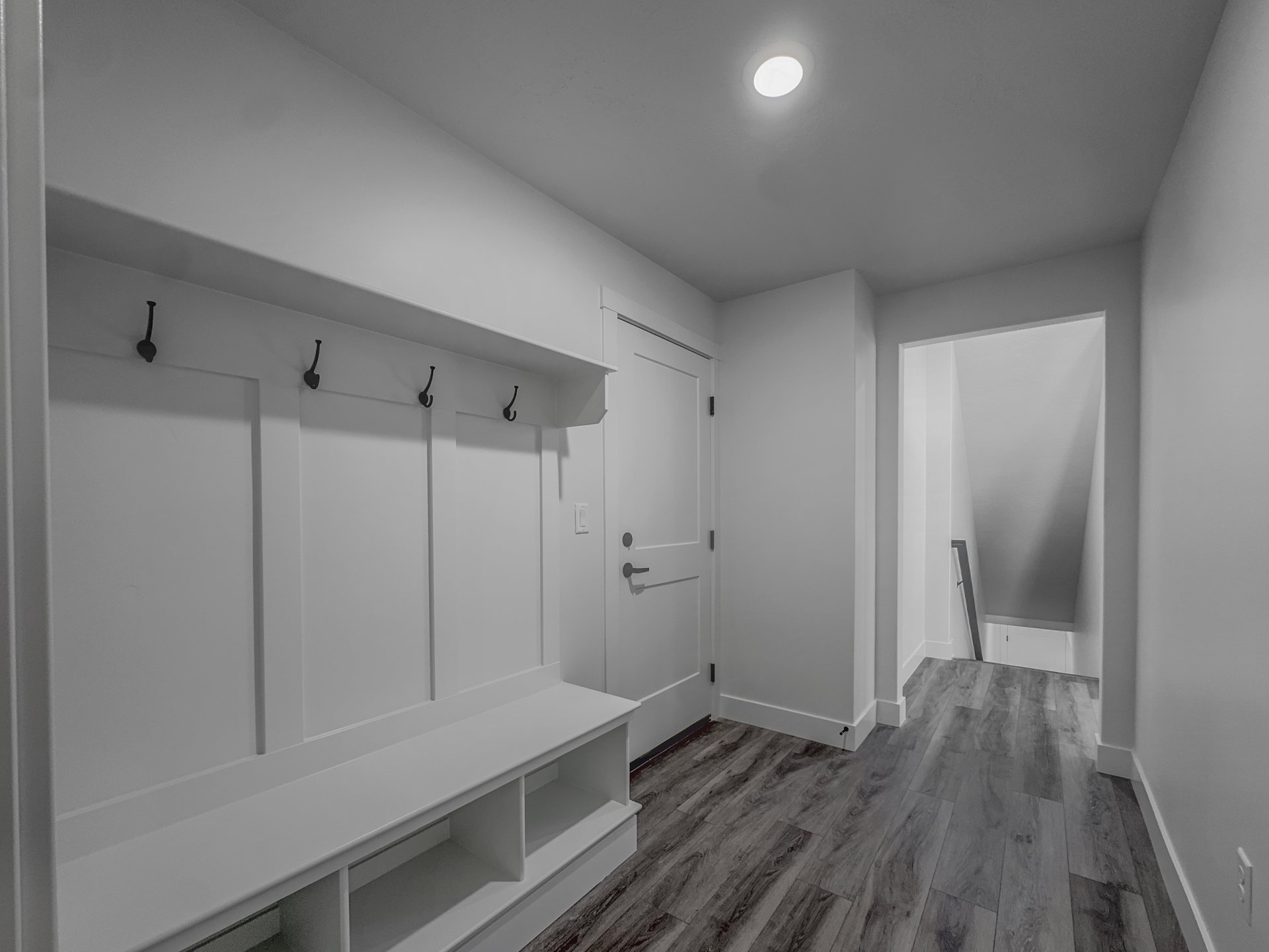Entryway featuring built-in storage bench with cubbies, board and batten wall paneling with hooks, and wood-finish flooring