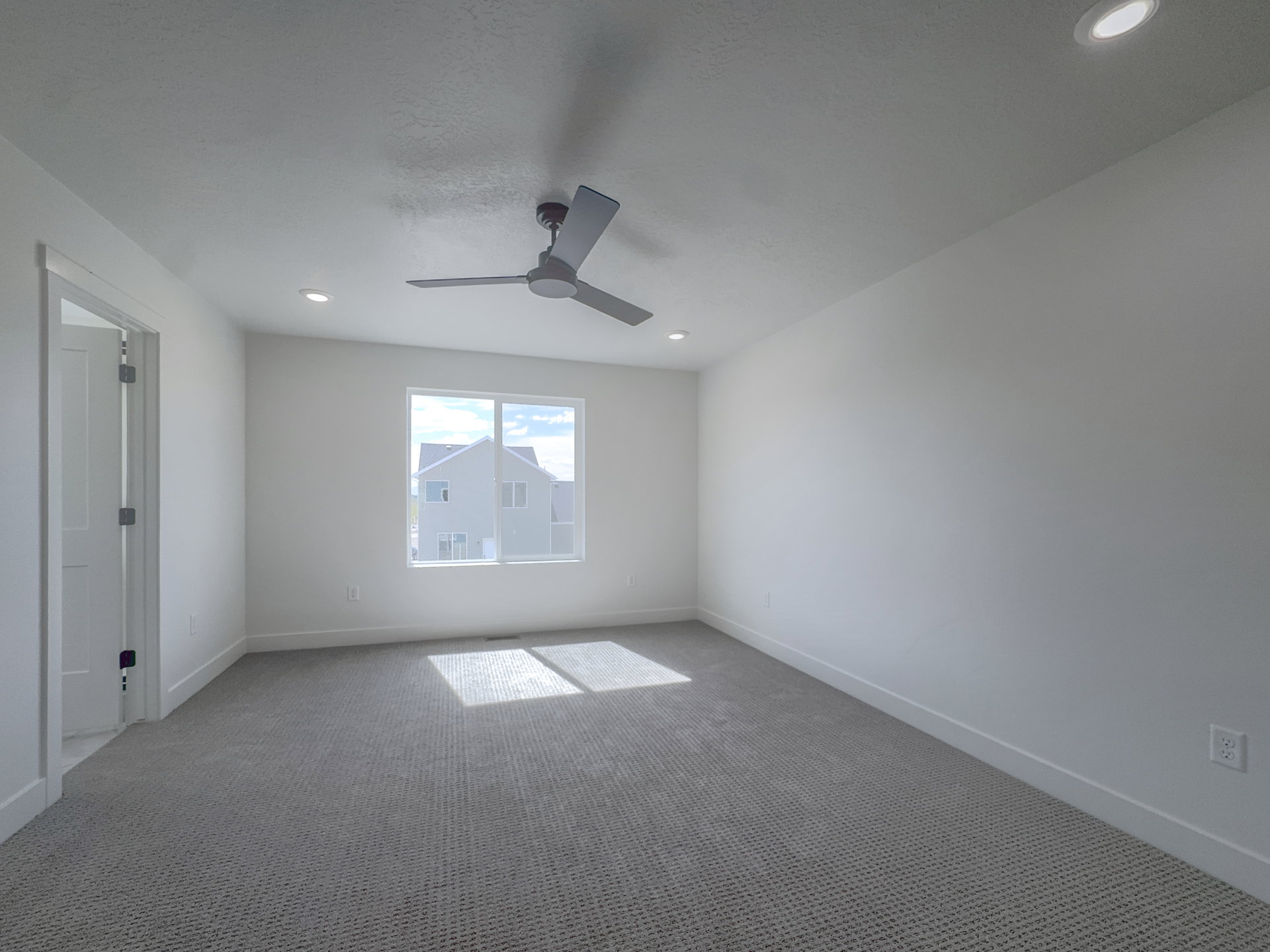 Spacious room featuring neutral carpeting, a modern ceiling fan, and recessed lighting