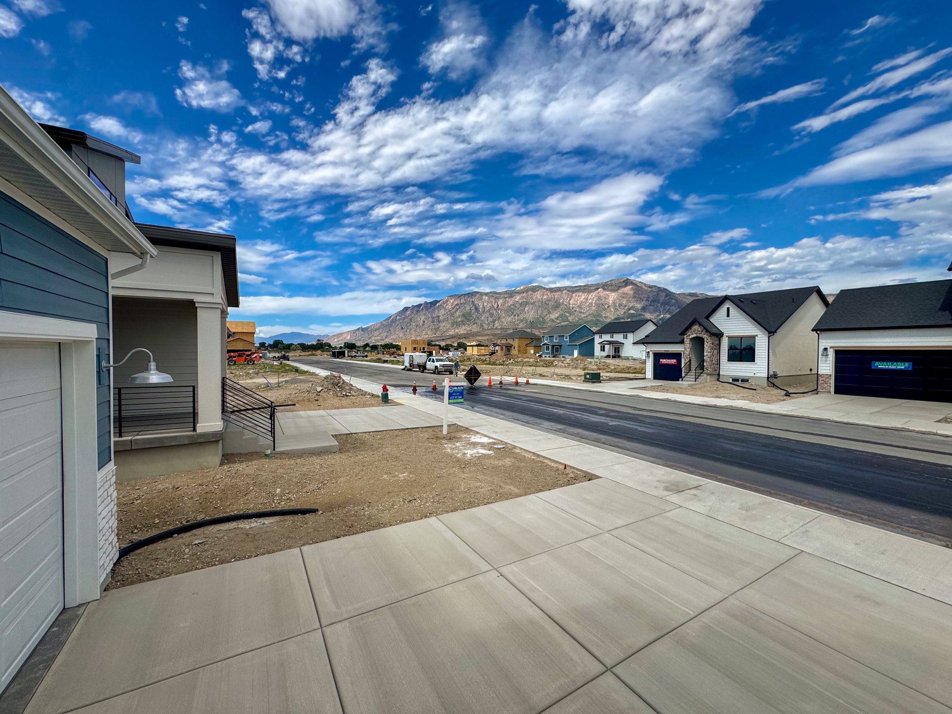 Newly constructed community featuring a paved street, concrete sidewalks, and properties with mountain scenery