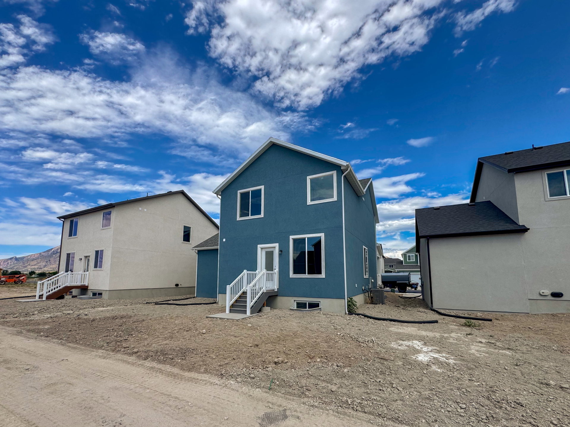 Two-story residence featuring a blue exterior, white trim windows, and a dark shingle roof