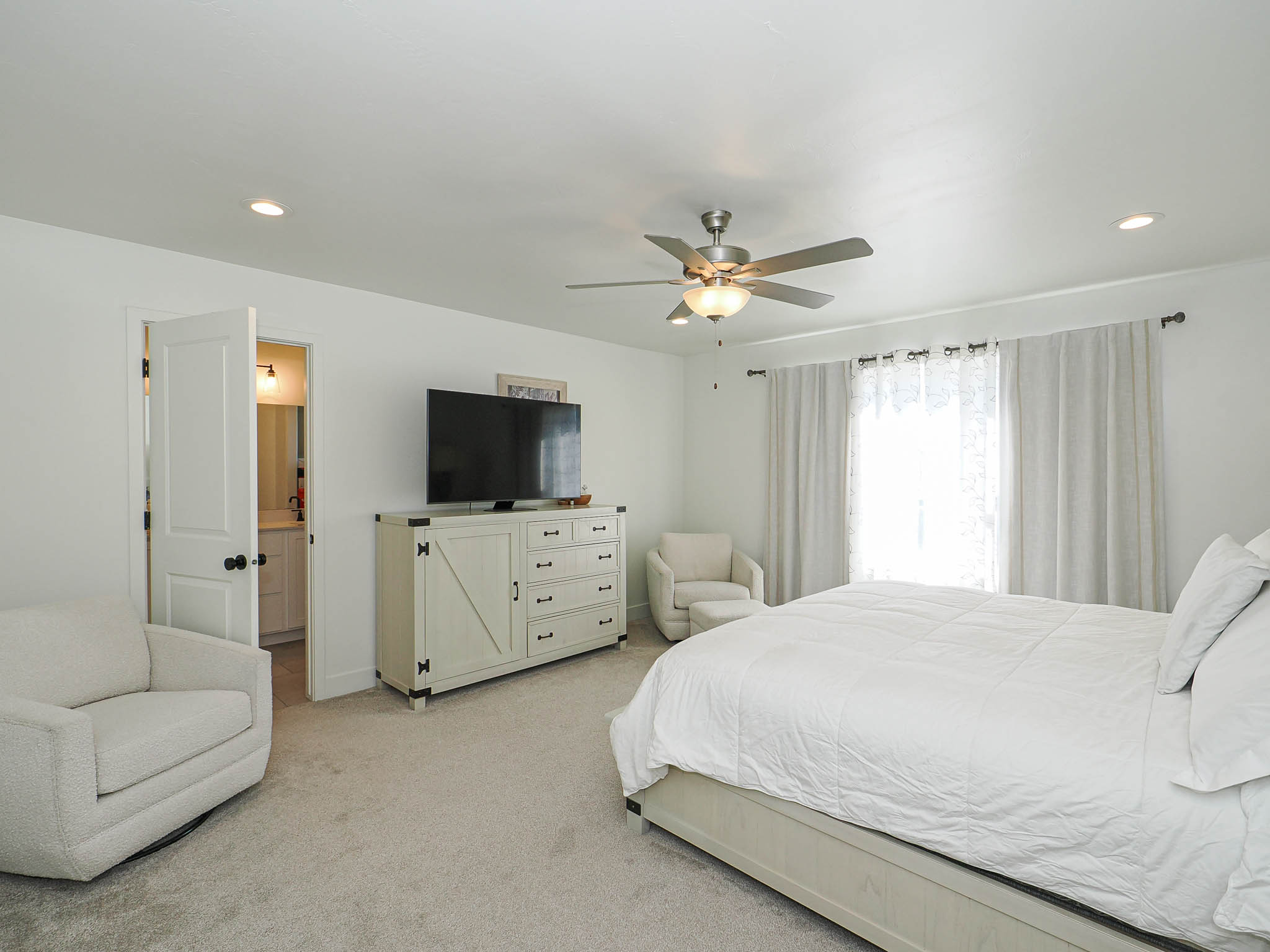 Recessed lighting, ceiling fan with integrated light, and large window with curtain rods