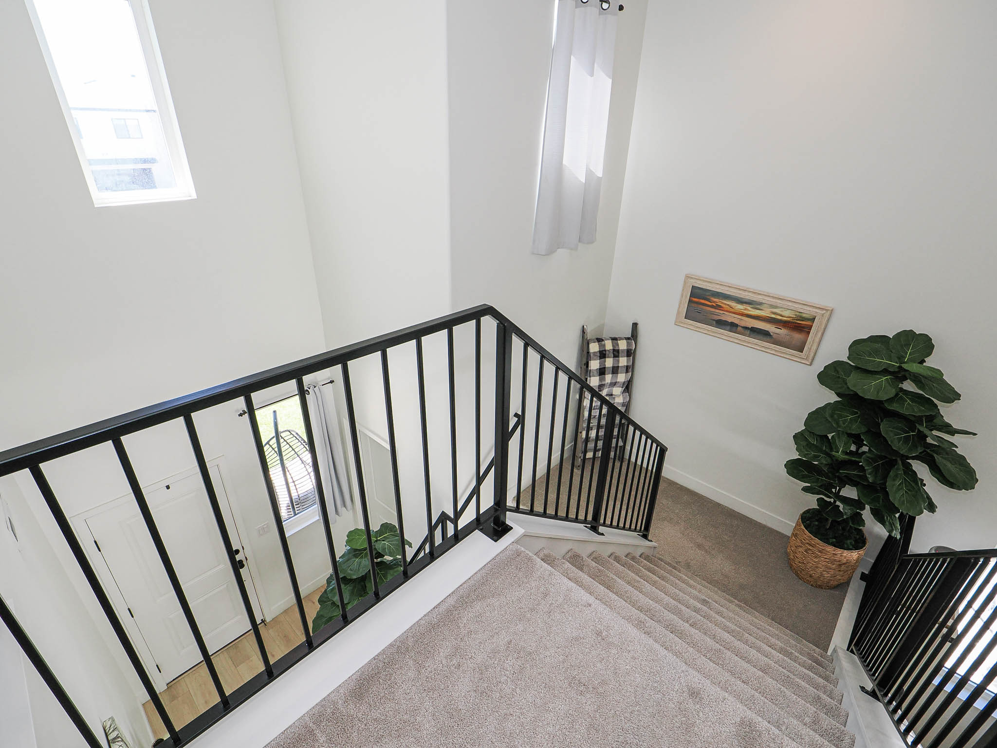 Multi-level interior featuring a carpeted staircase with contemporary black metal railings