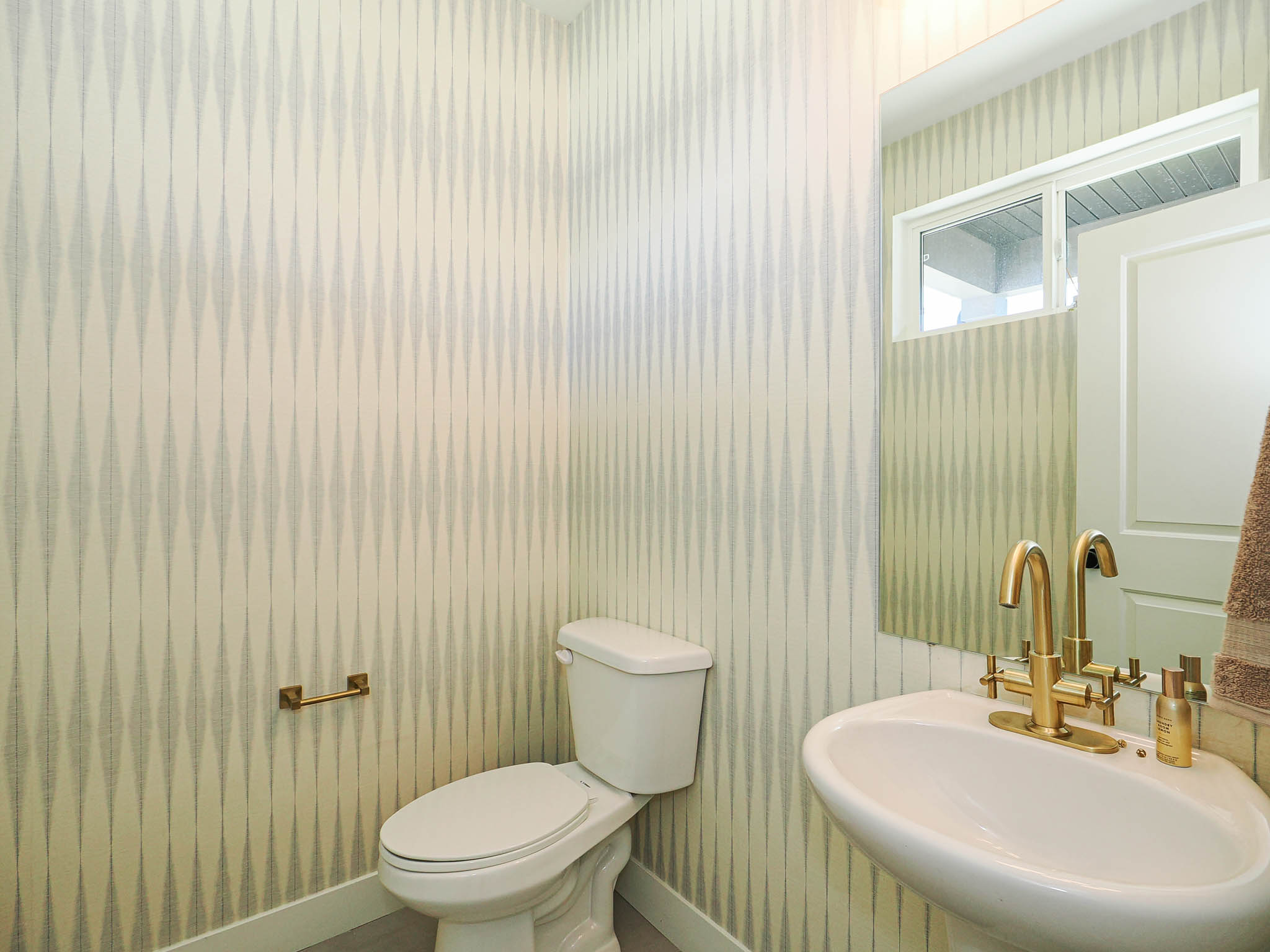 Wall-mounted pedestal sink with brass-finish faucet