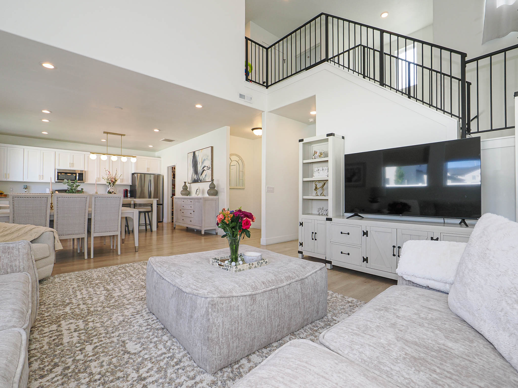 Open-concept living space featuring high ceilings, contemporary light wood-finish flooring, and recessed lighting