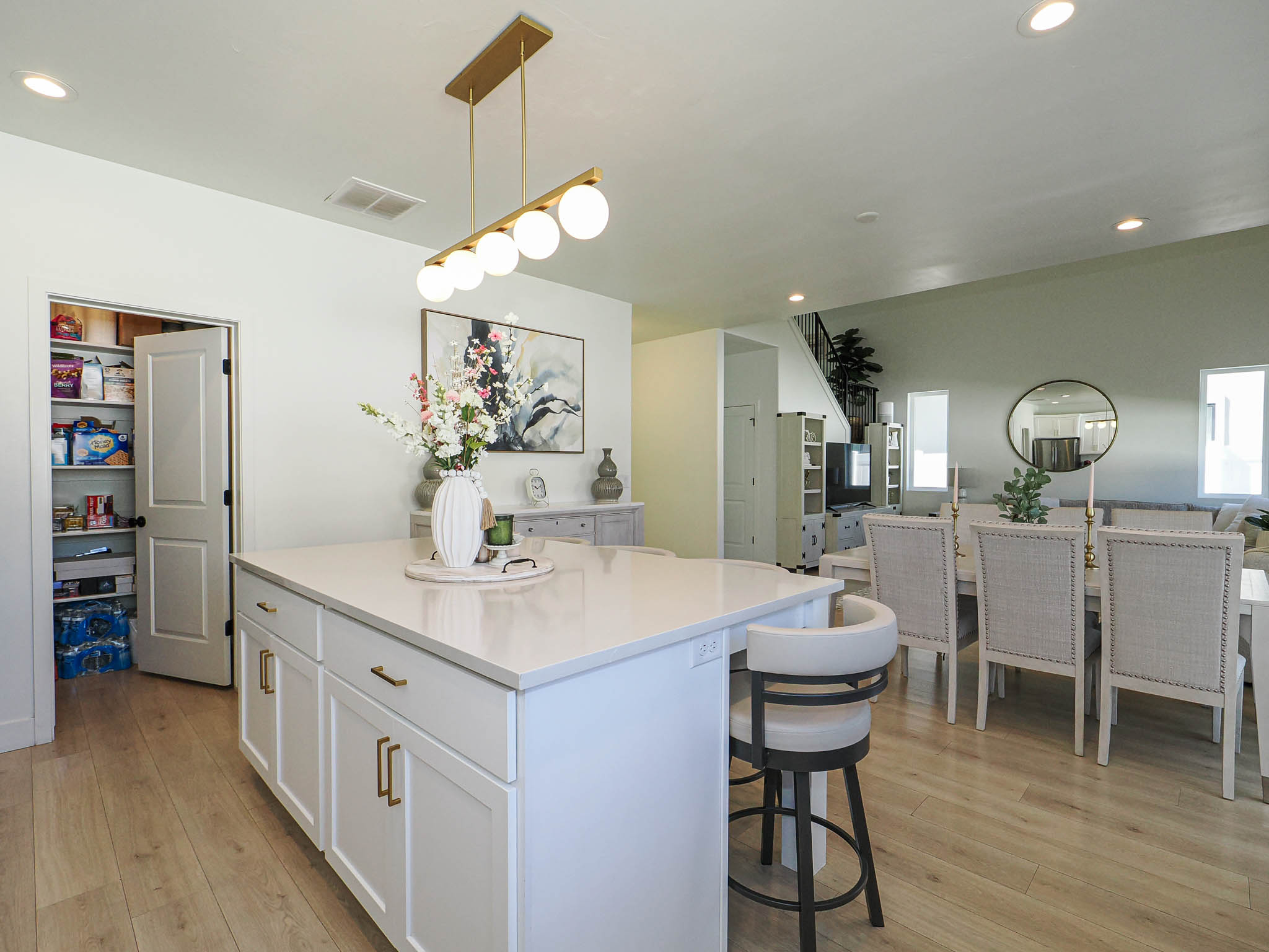 Open-concept living area featuring a kitchen island with a light-toned countertop, wood-finish flooring, recessed lighting, and a modern linear chandelier