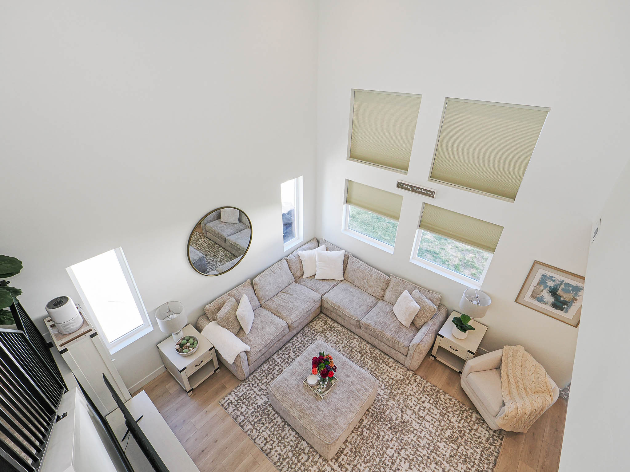 Vaulted living space featuring an L-shaped sectional, light wood-finish flooring, and multiple windows with roller shades